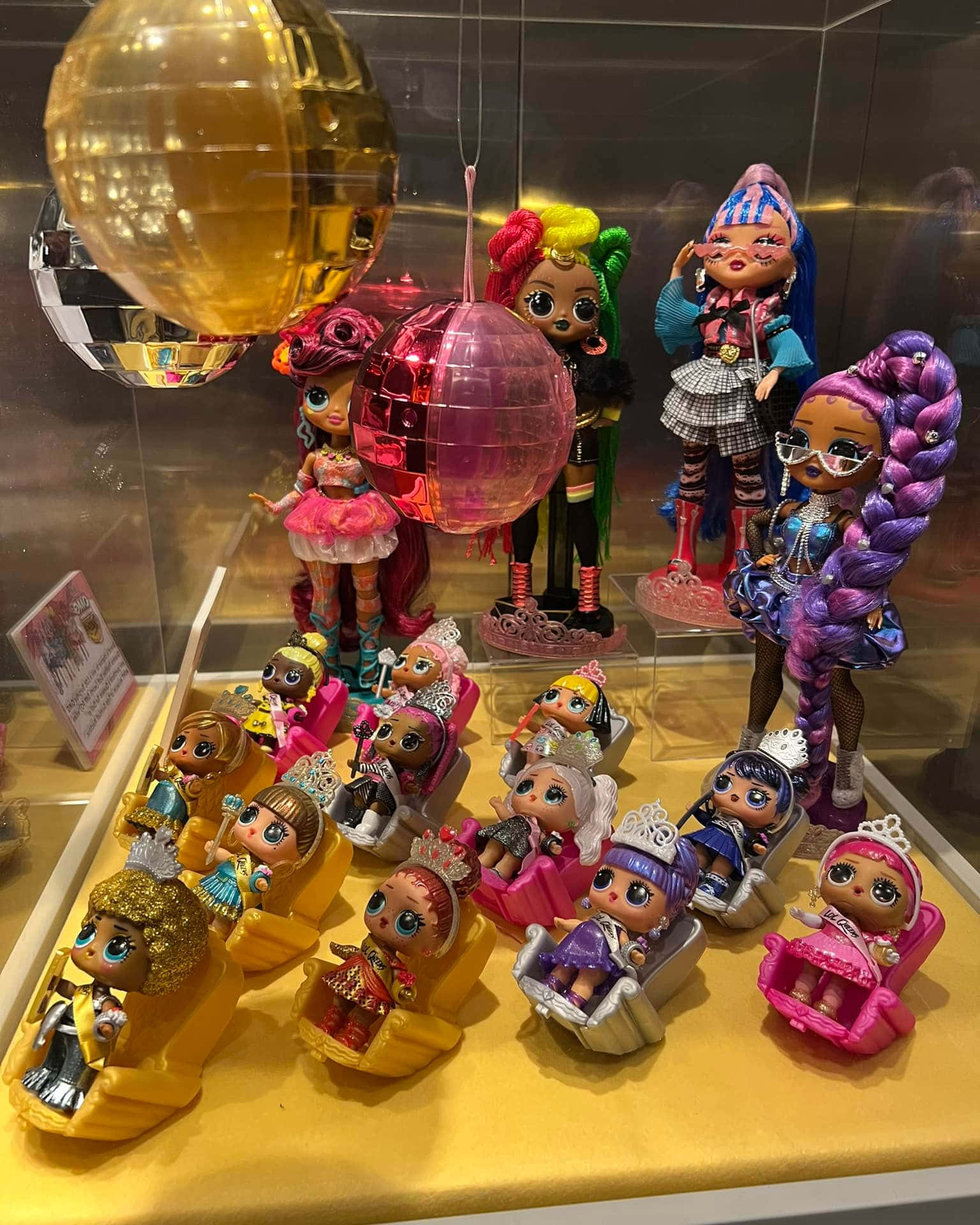Retro Toys 桌布 壁紙 — 玻璃展示櫃內，色彩繽紛的LOL Surprise公仔坐在彩色椅子上，上方有迪斯科球。
