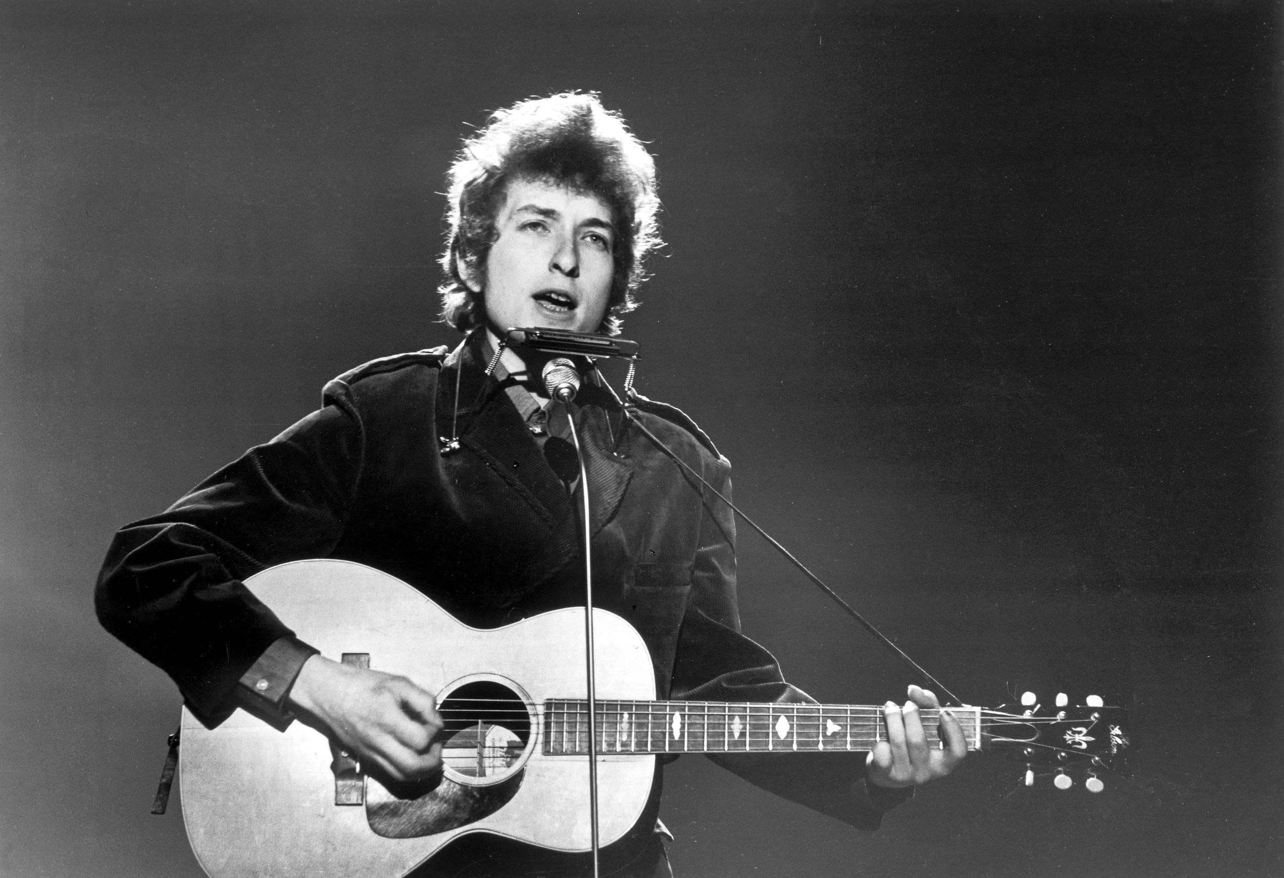 黑白 桌布 壁紙 — Bob Dylan 在戲劇性的聚光燈下熱情地拿著木吉他在舞台上表演。