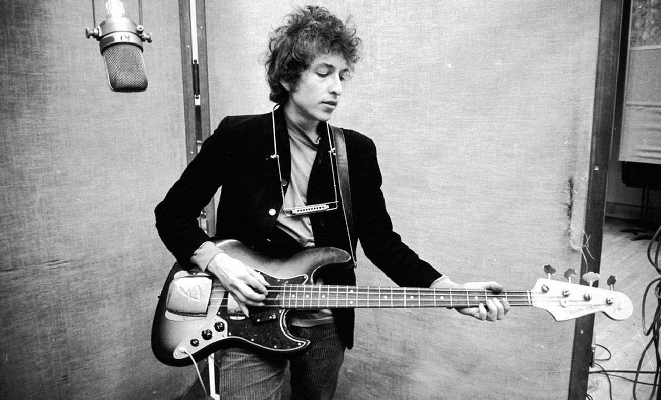 黑白 桌布 壁紙 — Bob Dylan 在錄音室彈奏低音吉他，上方懸掛著一個復古麥克風。