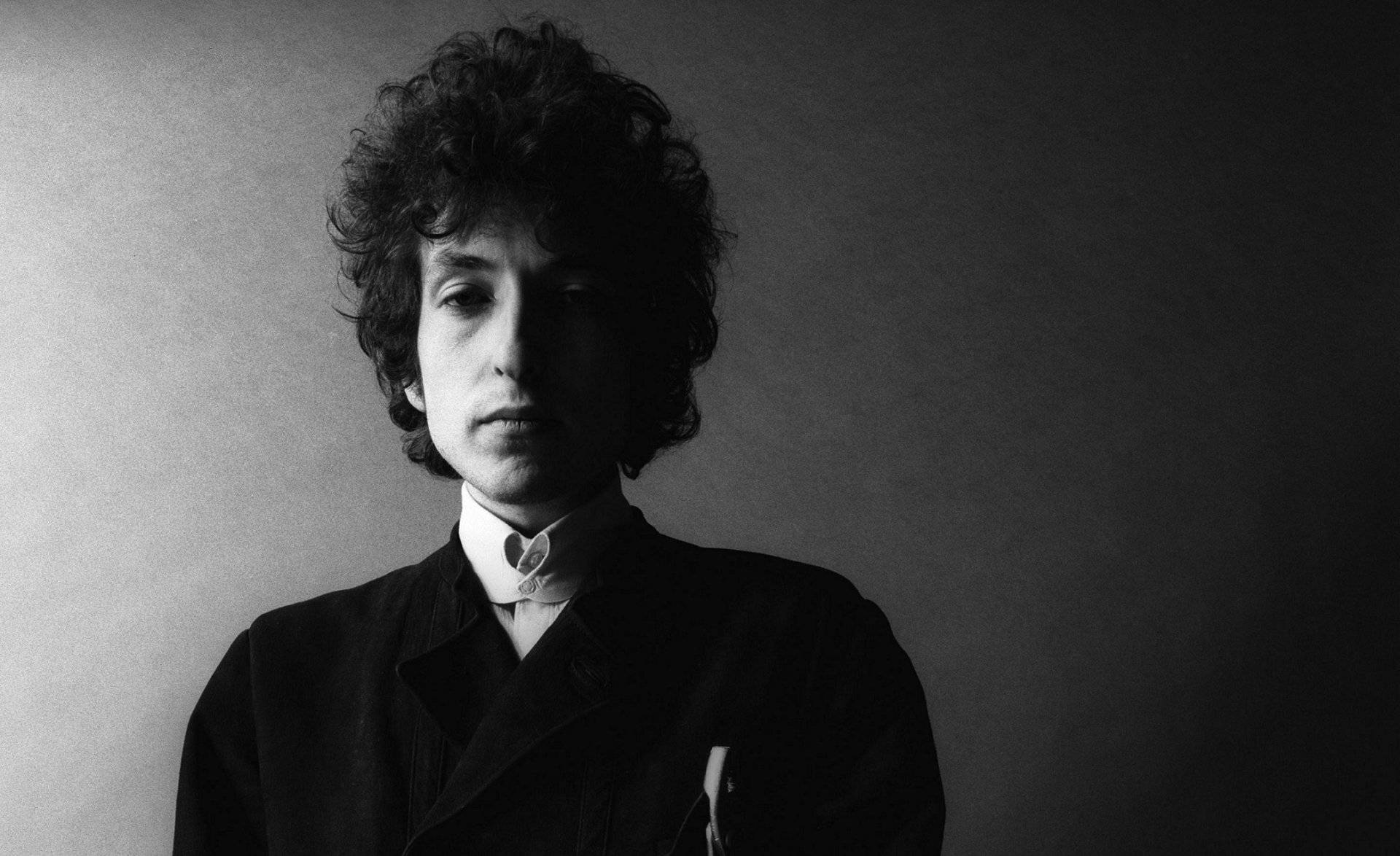 黑白 桌布 壁紙 — Bob Dylan 的黑白肖像，捲髮，表情嚴肅，背景為漸變灰色。