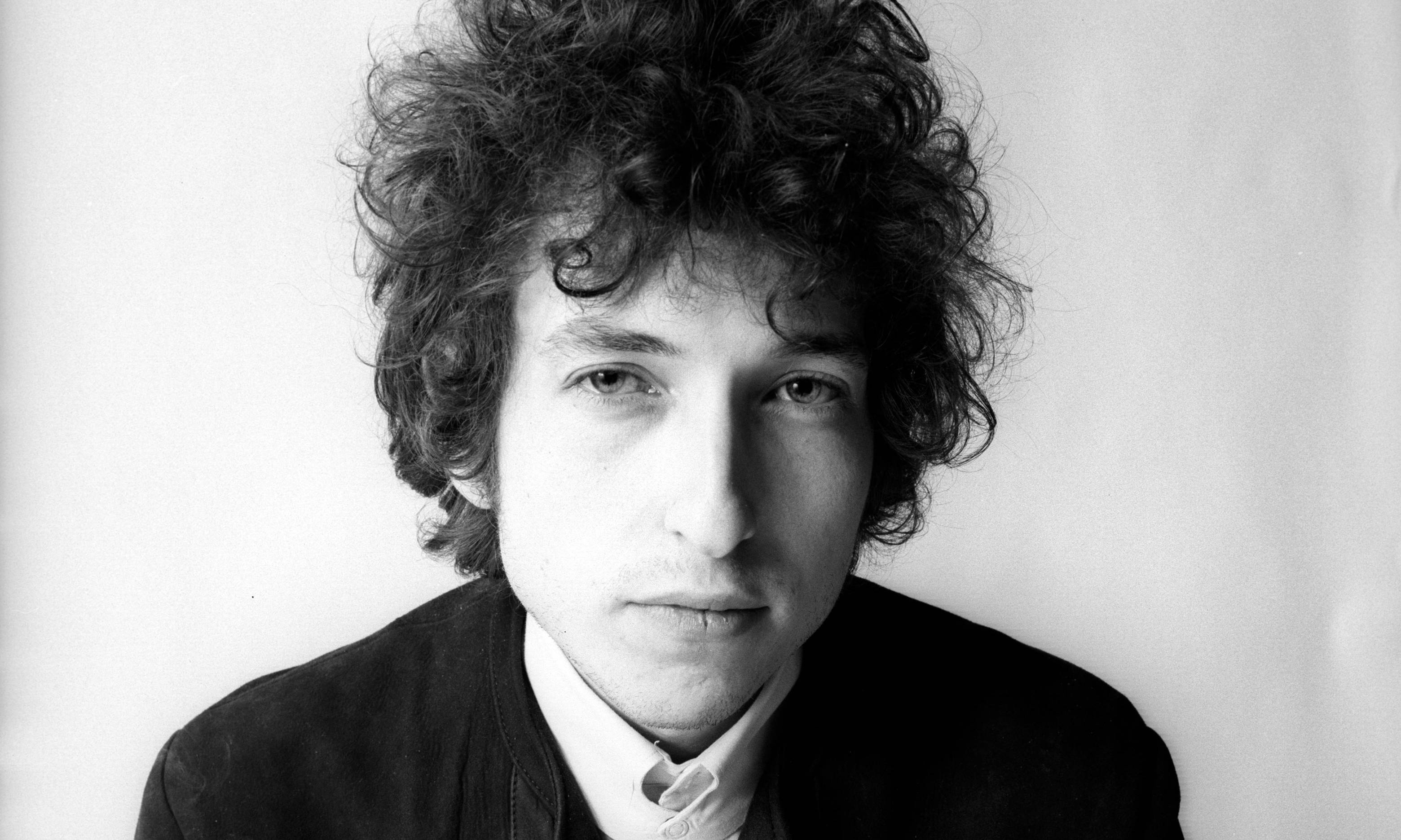 黑白 桌布 壁紙 — Bob Dylan 的黑色和白色肖像，頭髮捲曲，直視相機，背景簡單。