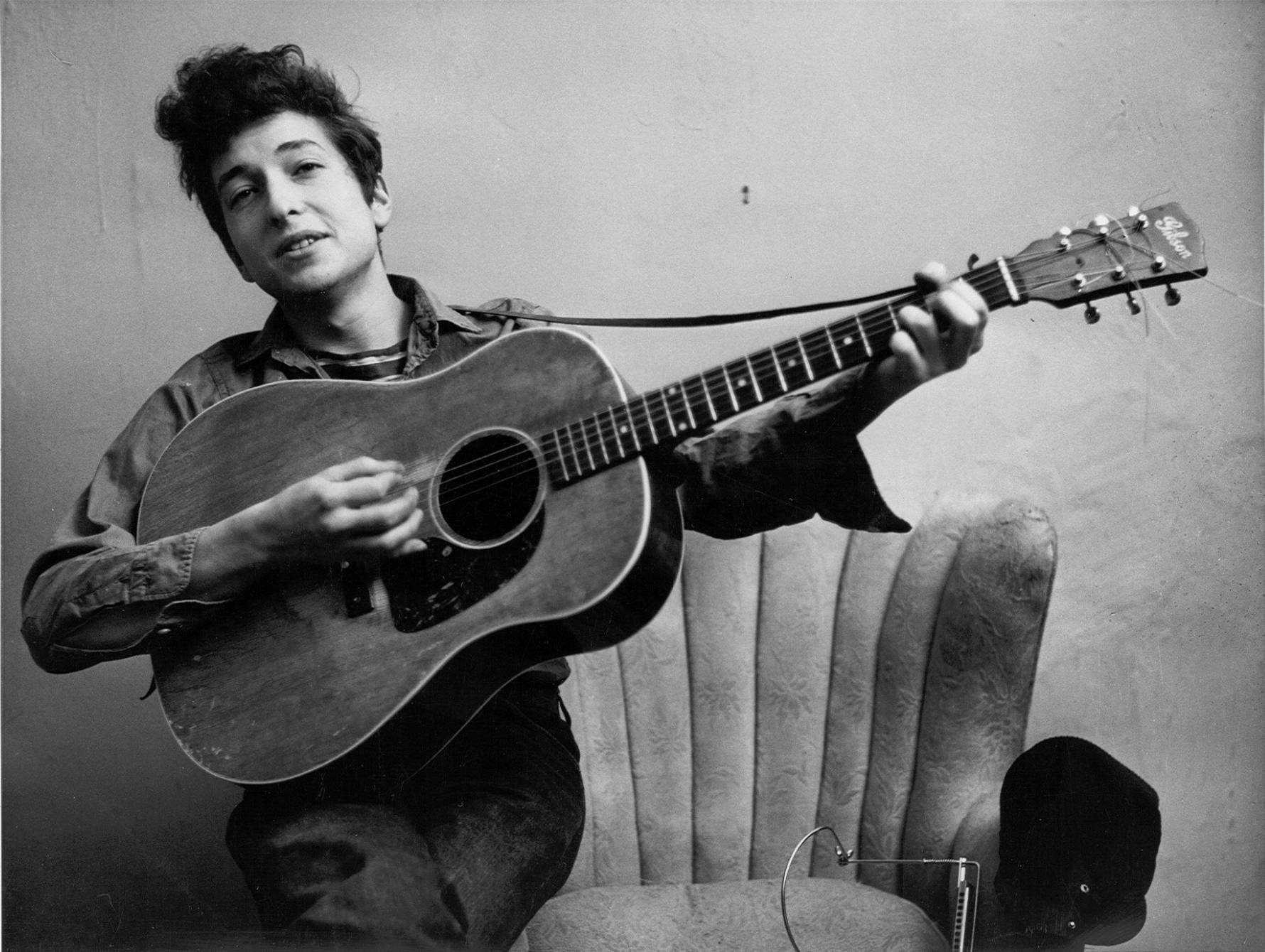 黑白 桌布 壁紙 — Bob Dylan 隨意地坐著，手持一把木吉他，是一張復古黑白肖像照。