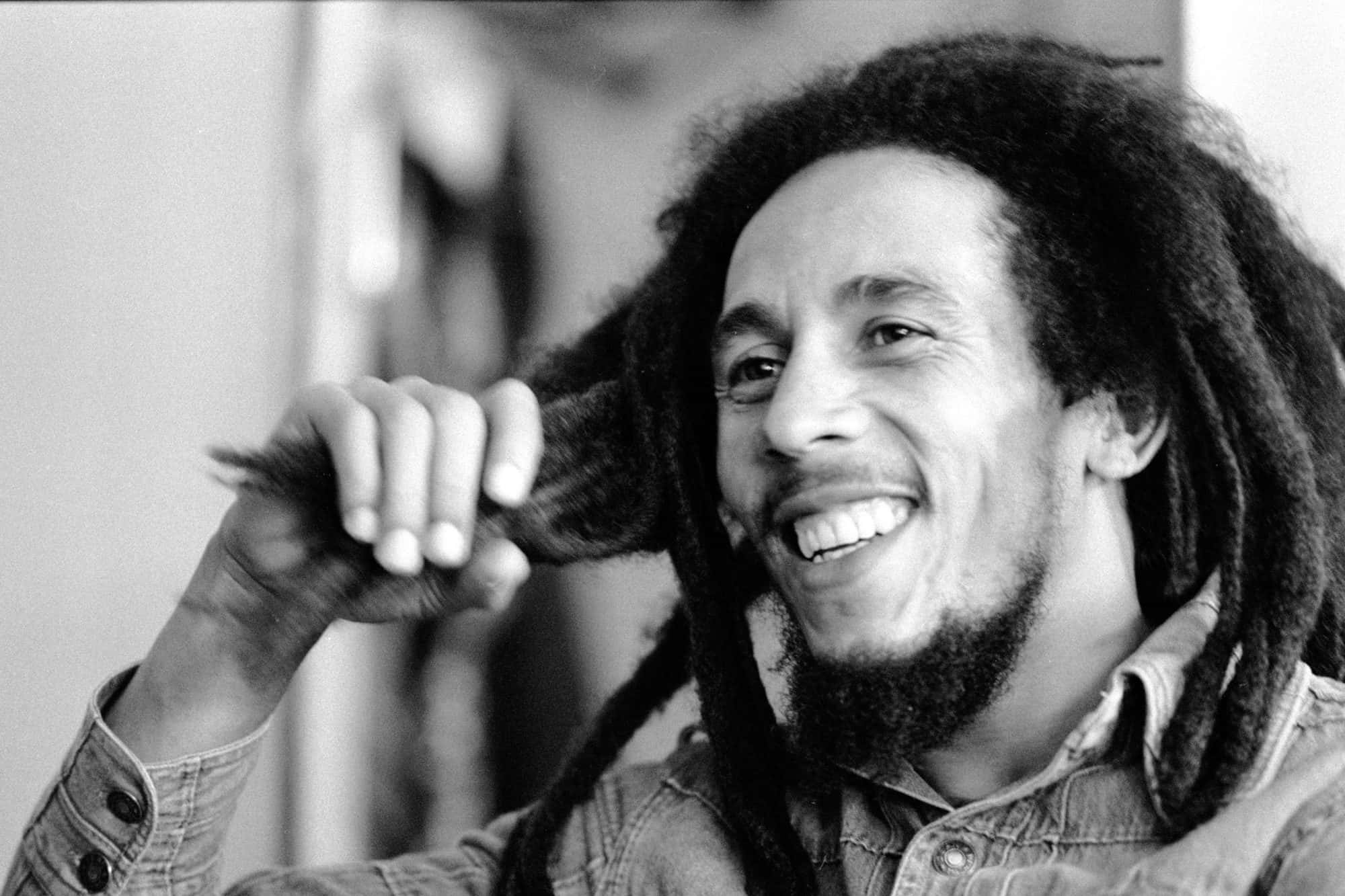 Bob Marley 桌布 壁紙 — Bob Marley 在黑白真誠肖像中，開心地笑著，同時頑皮地觸摸他的辮子。