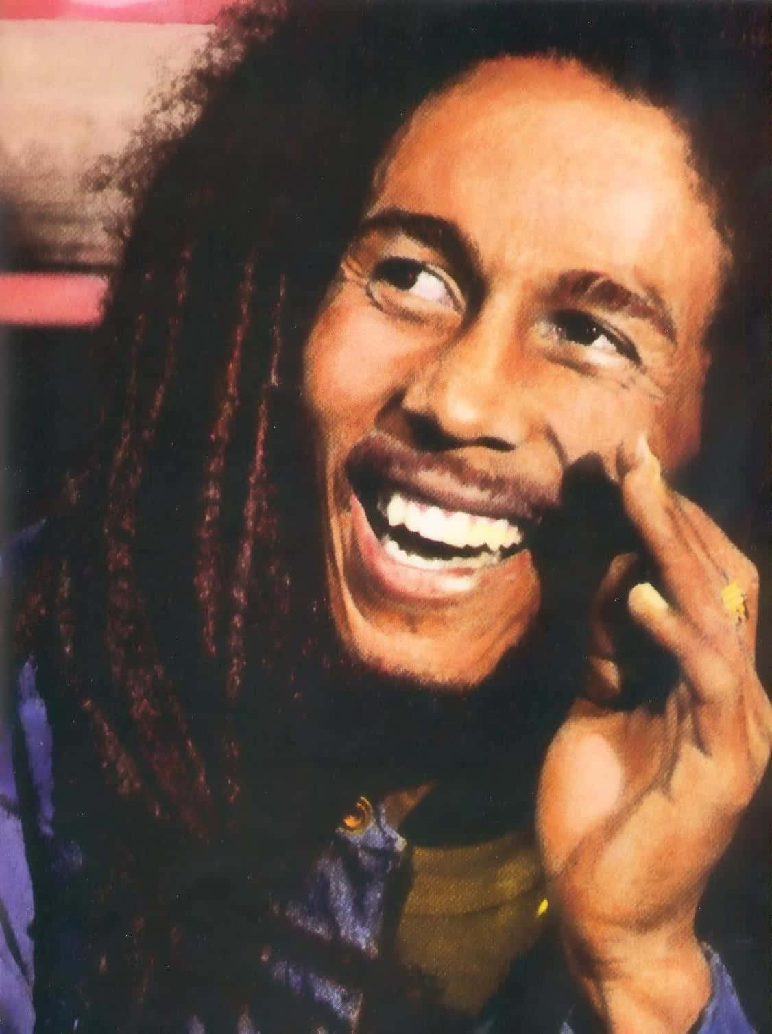 Bob Marley 桌布 壁紙 — Bob Marley 愉快地大笑，手靠近臉龐，他的辮子在溫暖燈光下襯托出燦爛的笑容。