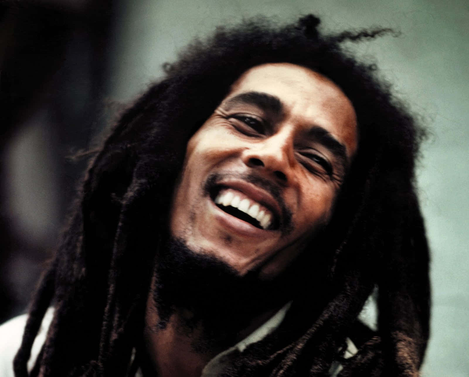 Bob Marley 桌布 壁紙 — Bob Marley 愉快地大笑，他標誌性的辮子襯托出他燦爛的笑容。
