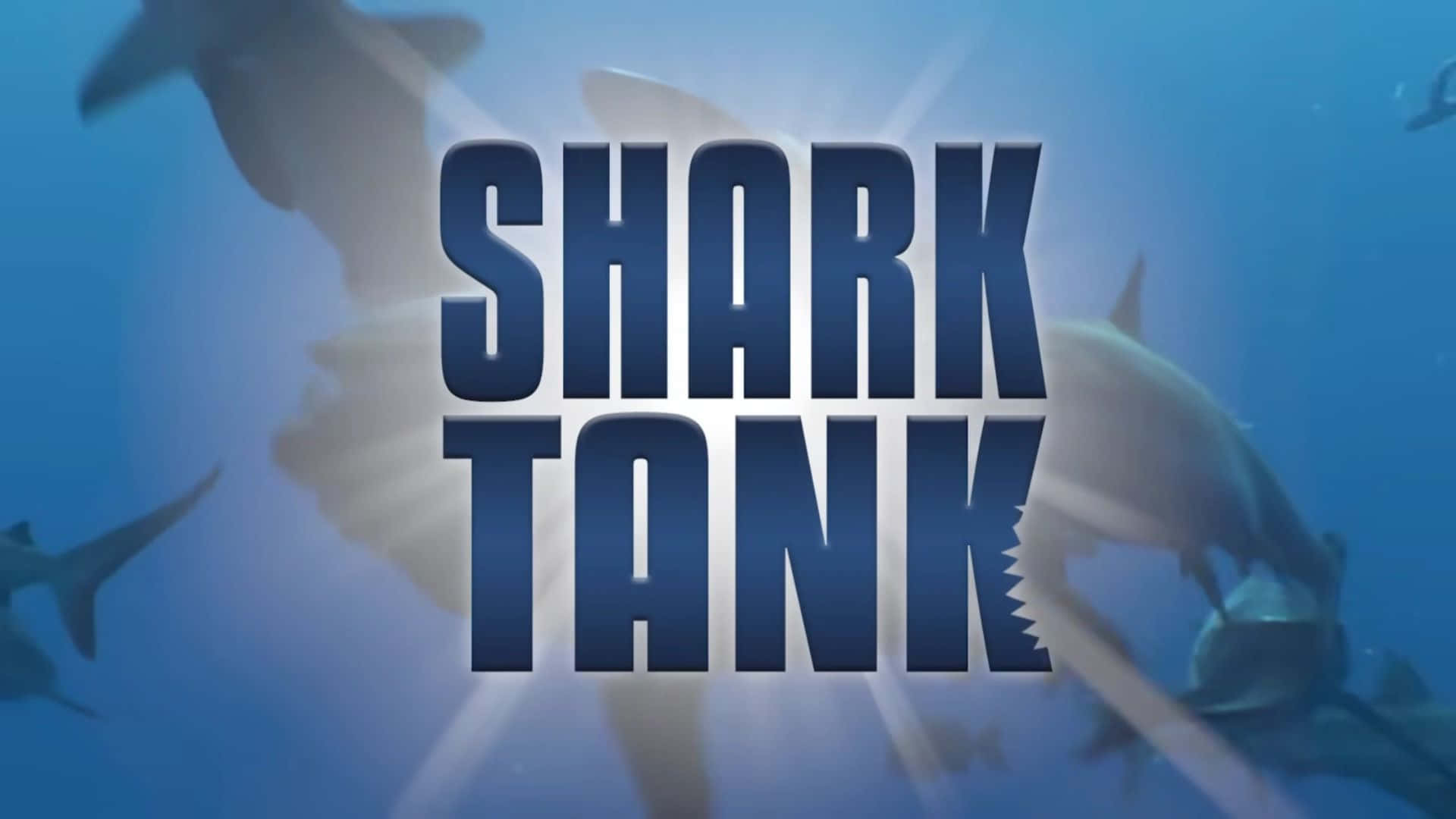 壁紙 — 大膽的藍色「SHARK TANK」文字在陽光照射的海水中游動的鯊魚背景下發光。
