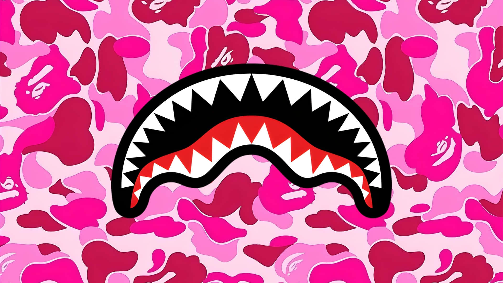  壁紙 — 一個大膽的鯊魚嘴標誌，帶有鋒利的牙齒，置於充滿活力的粉紅色迷彩背景上。