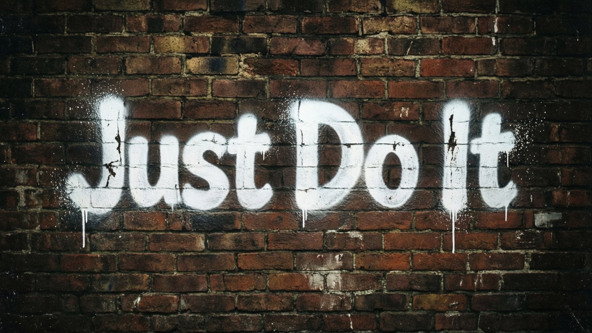 就去做吧 桌布 壁紙 — 大膽的白色塗鴉寫著「Just Do It」，在昏暗燈光下沿著風化的紅磚牆滴落。