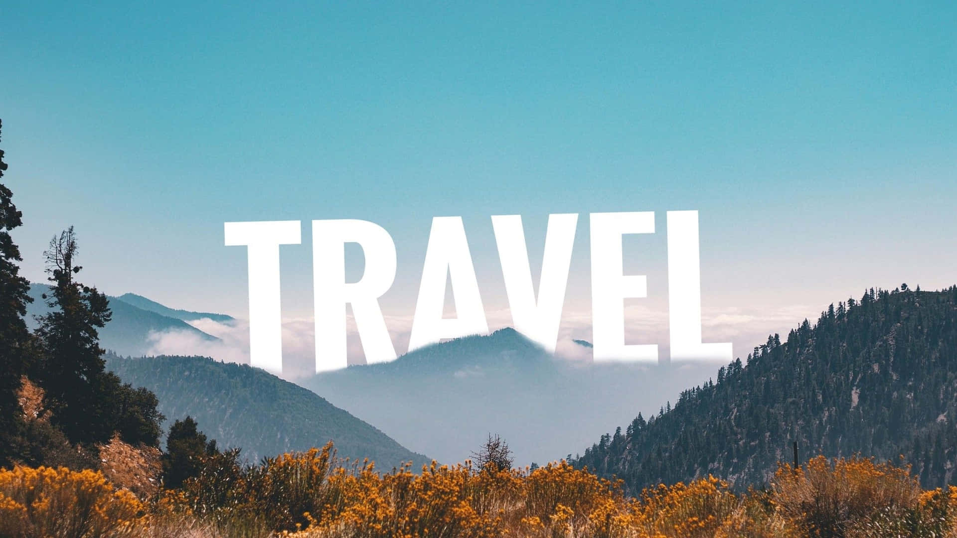  壁紙 — 在晴朗藍天下，霧氣繚繞的山脈和金色灌木之上，粗體白色「TRAVEL」文字。