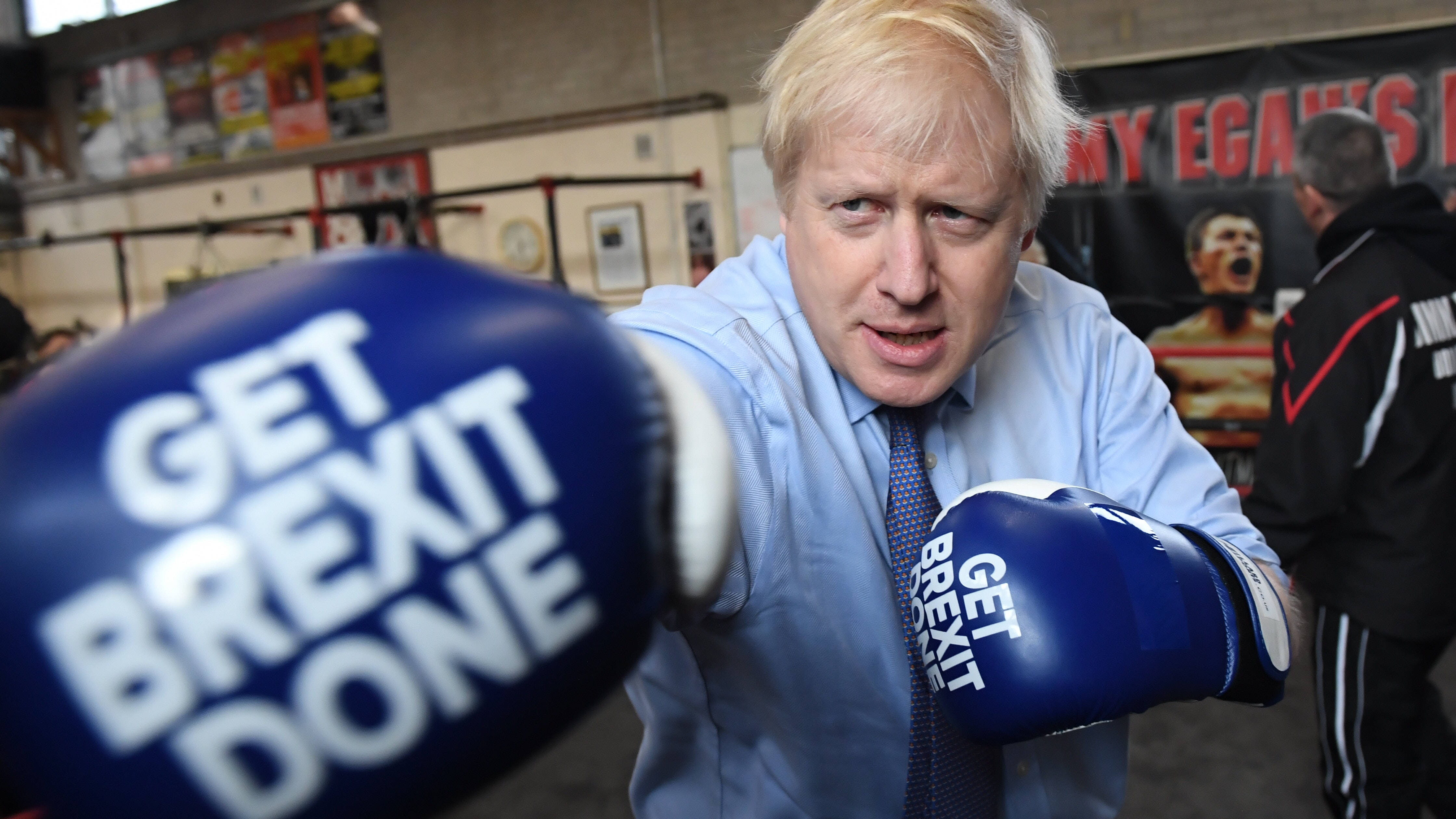 Boris Johnson 桌布 壁紙 — Boris Johnson 在拳擊健身房戴上藍色手套，帶有「GET BREXIT DONE」字樣，擺姿勢拍照。
