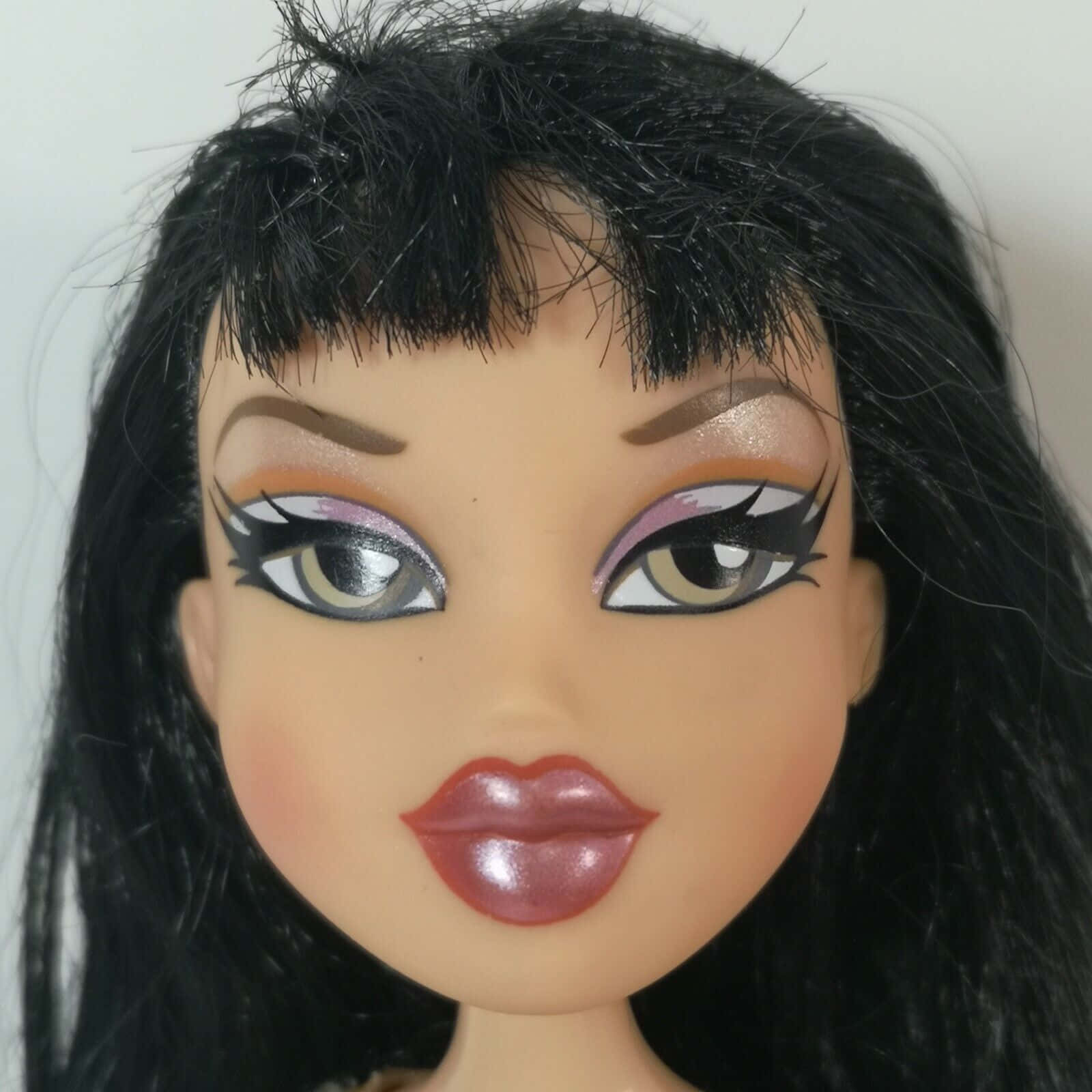 bratz 美學 桌布 壁紙 — Bratz 娃娃的特寫，有著大膽的妝容、黑髮和光澤的嘴唇，背景是純色。