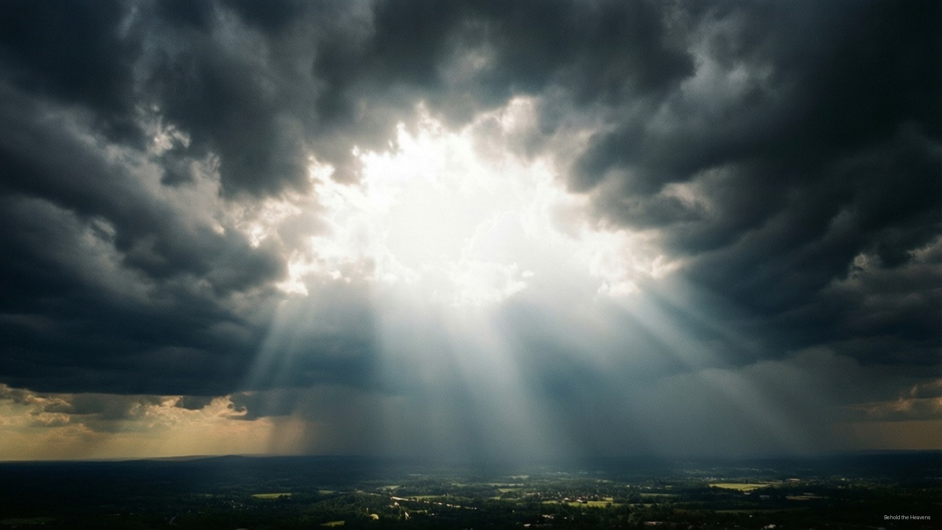 Heavens Opened 壁紙 — 明亮的陽光穿透黑暗的暴風雲，照亮下方廣闊的風景。