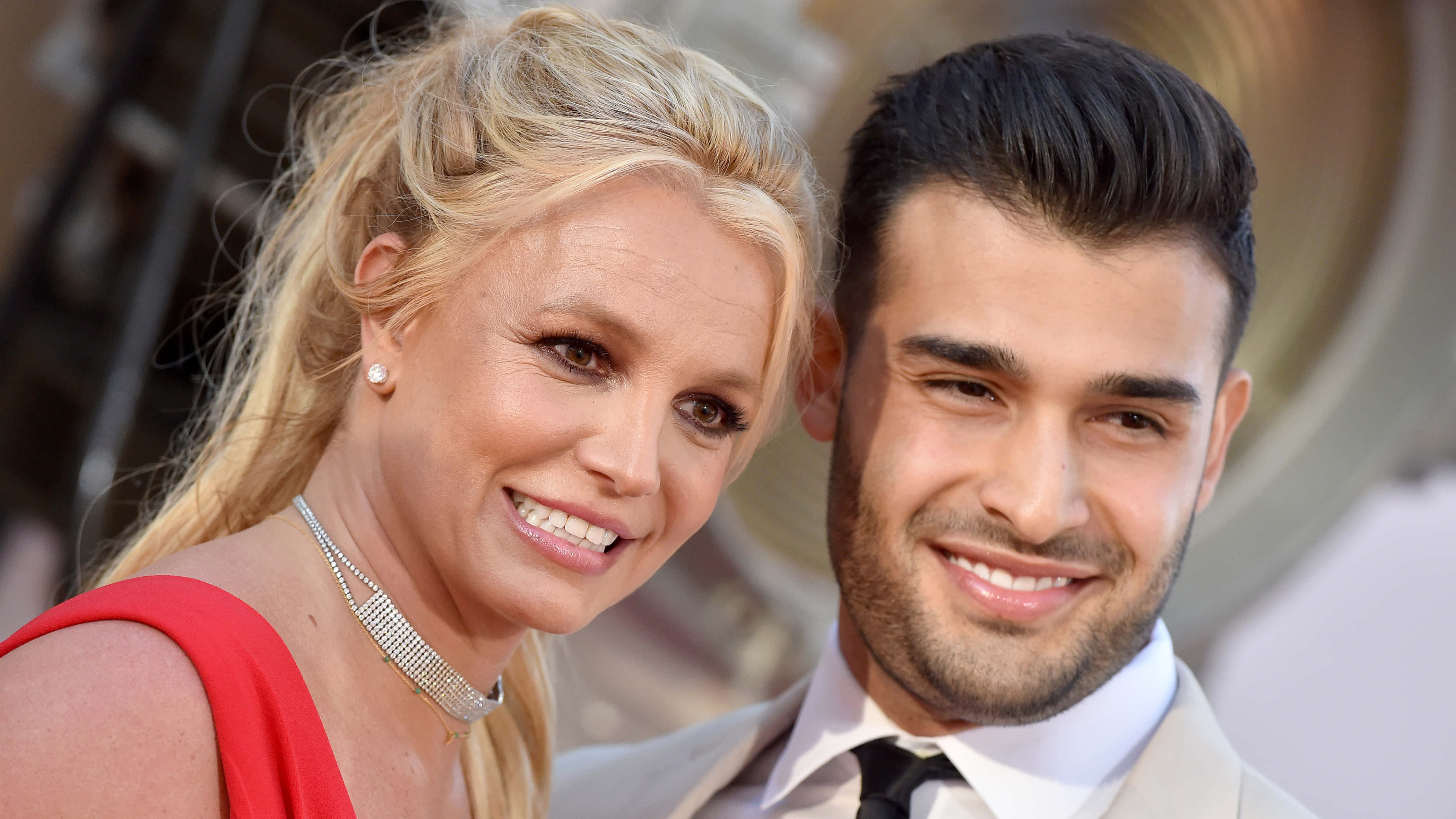 Britney Spears 桌布 壁紙 — Britney Spears 和 Sam Asghari 在紅地毯活動中穿著華麗的正裝，對著鏡頭燦爛微笑。