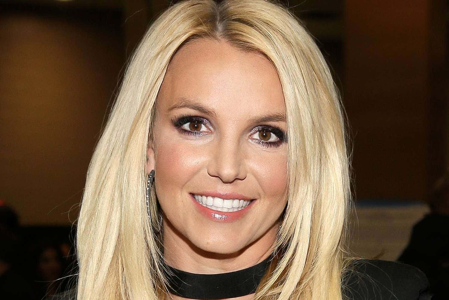 Britney Spears 桌布 壁紙 — Britney Spears 在特寫肖像中露出燦爛笑容，長長的金髮和大膽的眼妝。