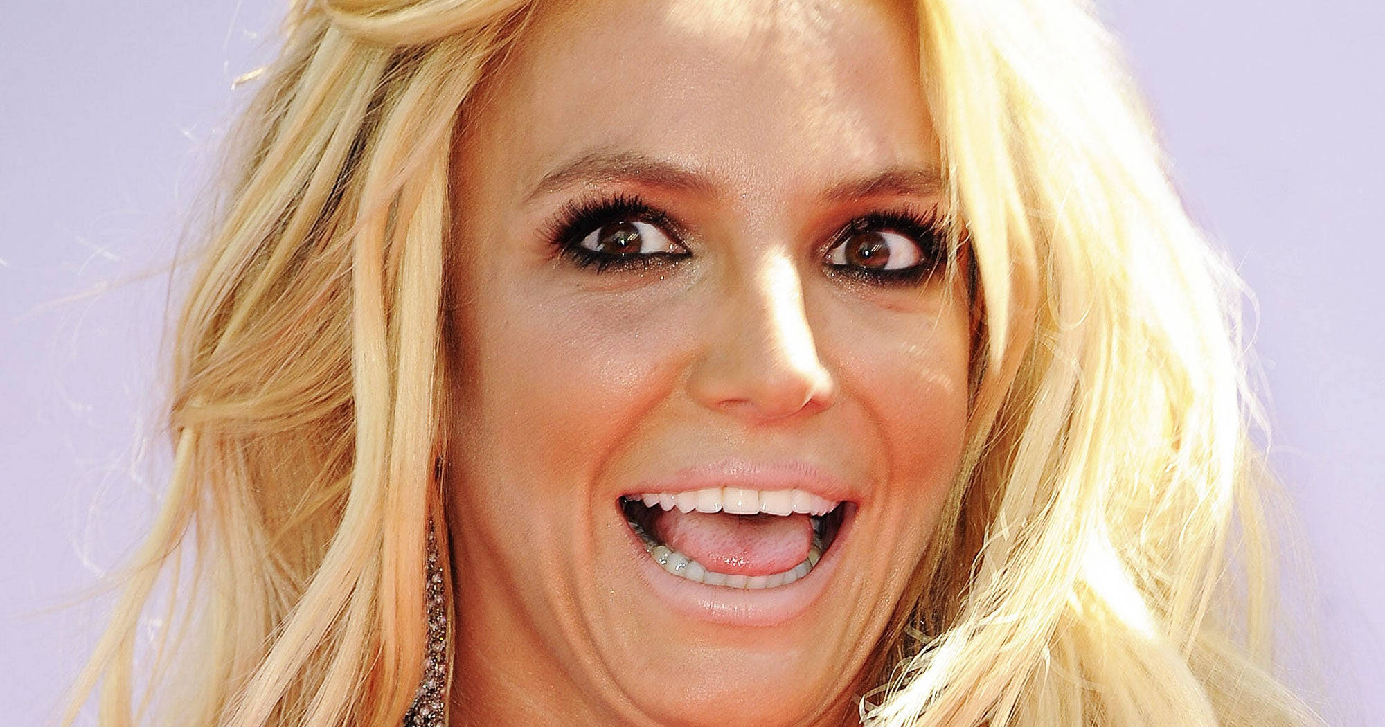 faces 桌布 壁紙 — Britney Spears 在柔和的薰衣草背景下，睜大眼睛、張嘴微笑，散發光芒。