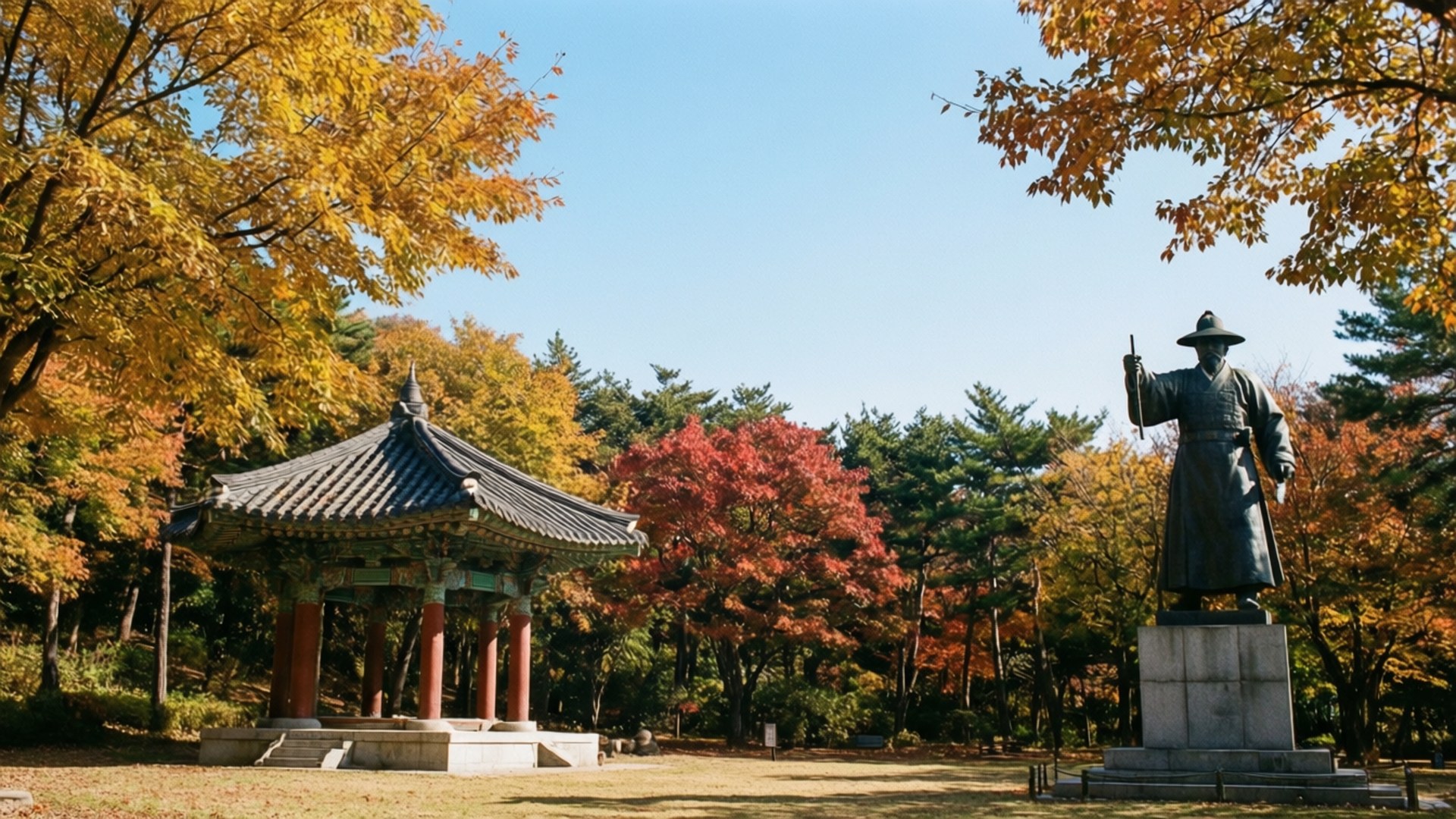 Yongdusan Park Autumn 壁紙 — 一座歷史人物的銅像矗立在傳統韓國亭子旁邊，周圍是色彩繽紛的秋樹。
