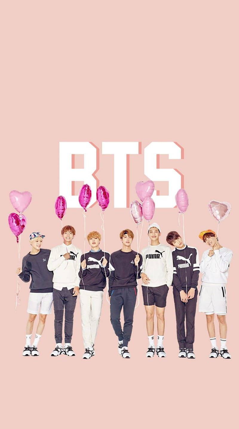 壁紙 — BTS 七位成員站成一排，手持粉紅色心形氣球，背景是柔和的粉紅色，上方有大型白色 'BTS' 字母。