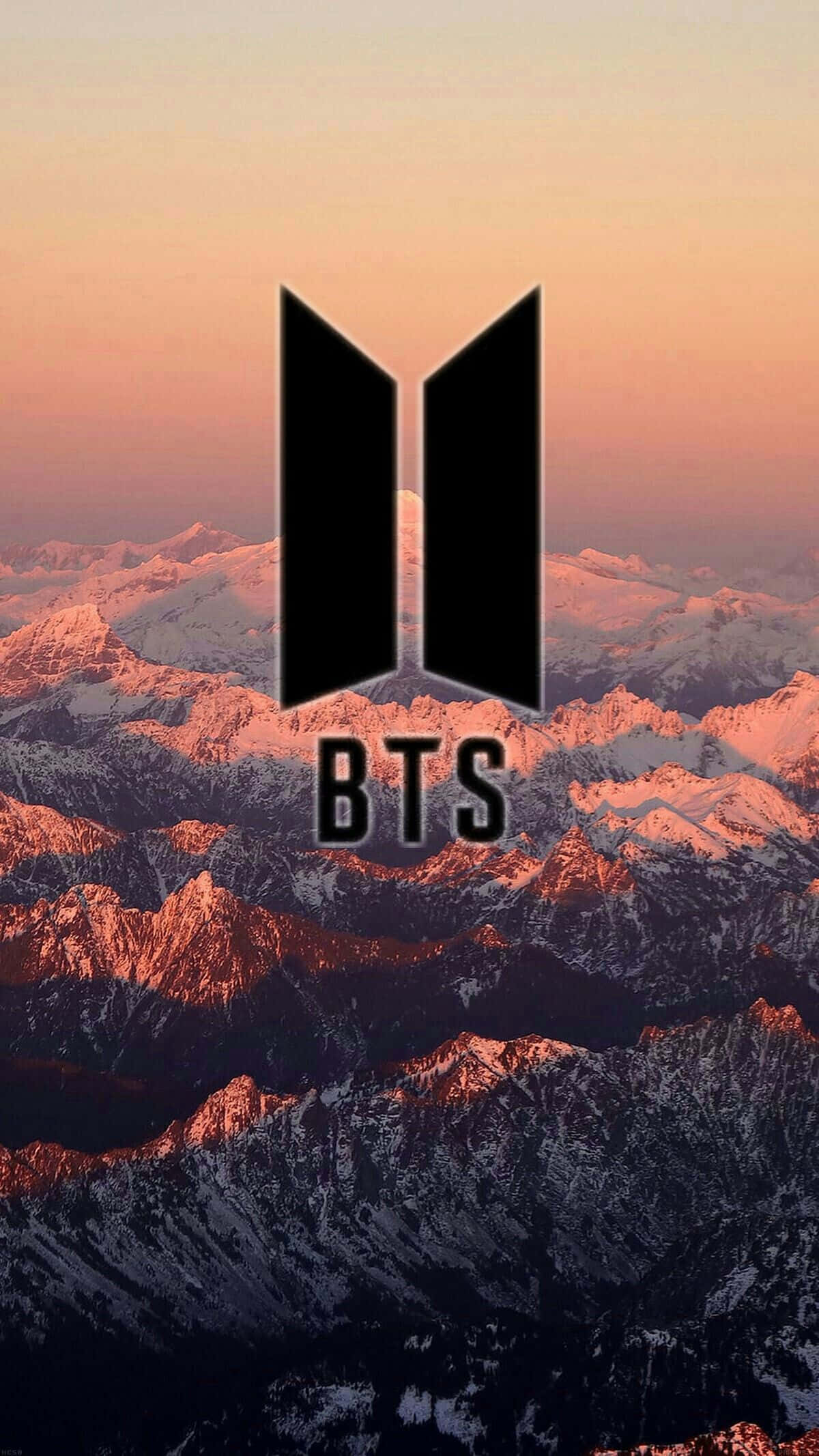 BTS 桌布 壁紙 — BTS標誌在溫暖的日落色調中，雄偉地矗立在白雪覆蓋的山脈前。