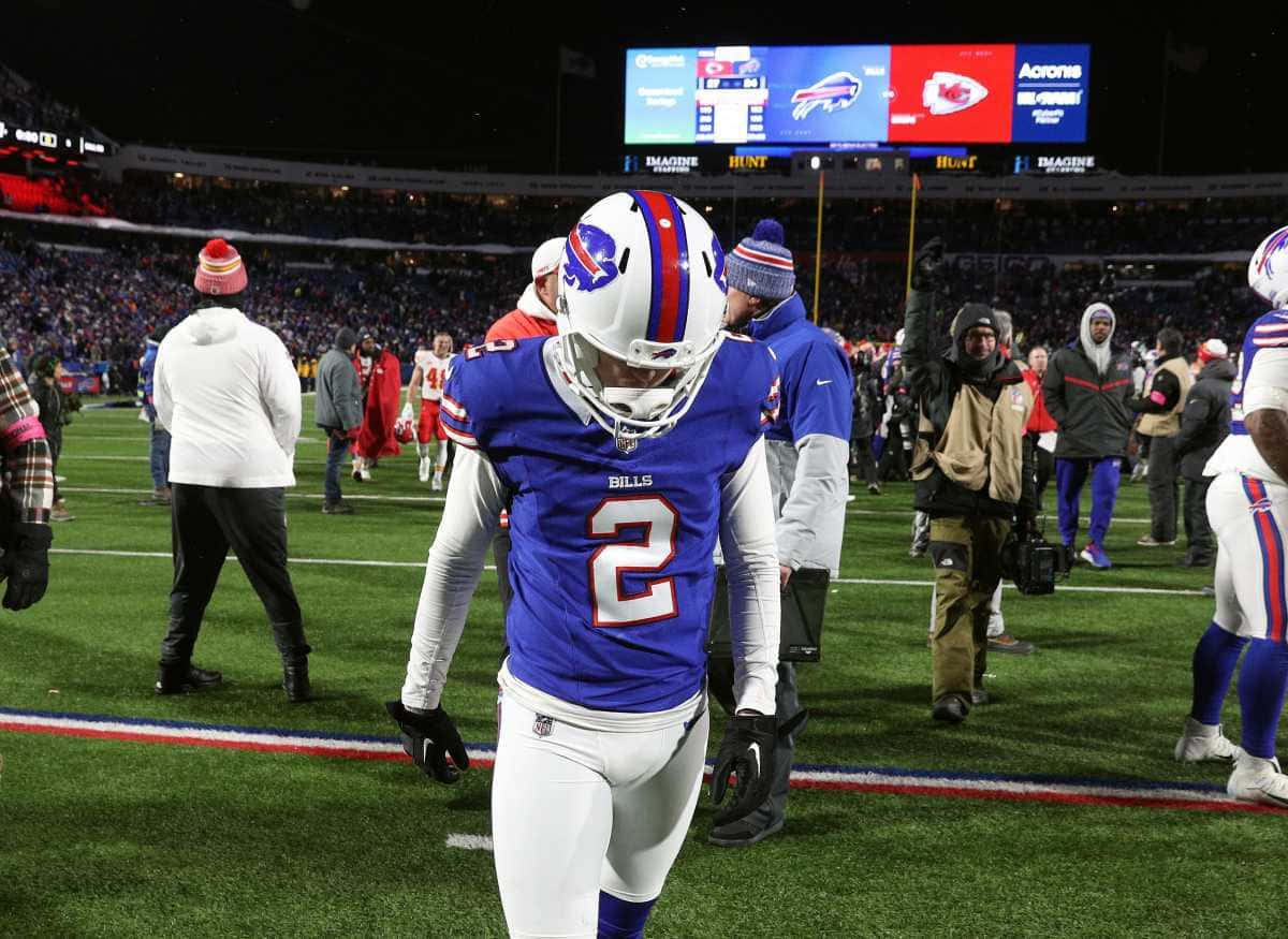  壁紙 — 一名身穿藍白球衣的 Buffalo Bills 美式足球員在夜晚的球場燈光下，在球迷和工作人員的圍繞下離開球場。