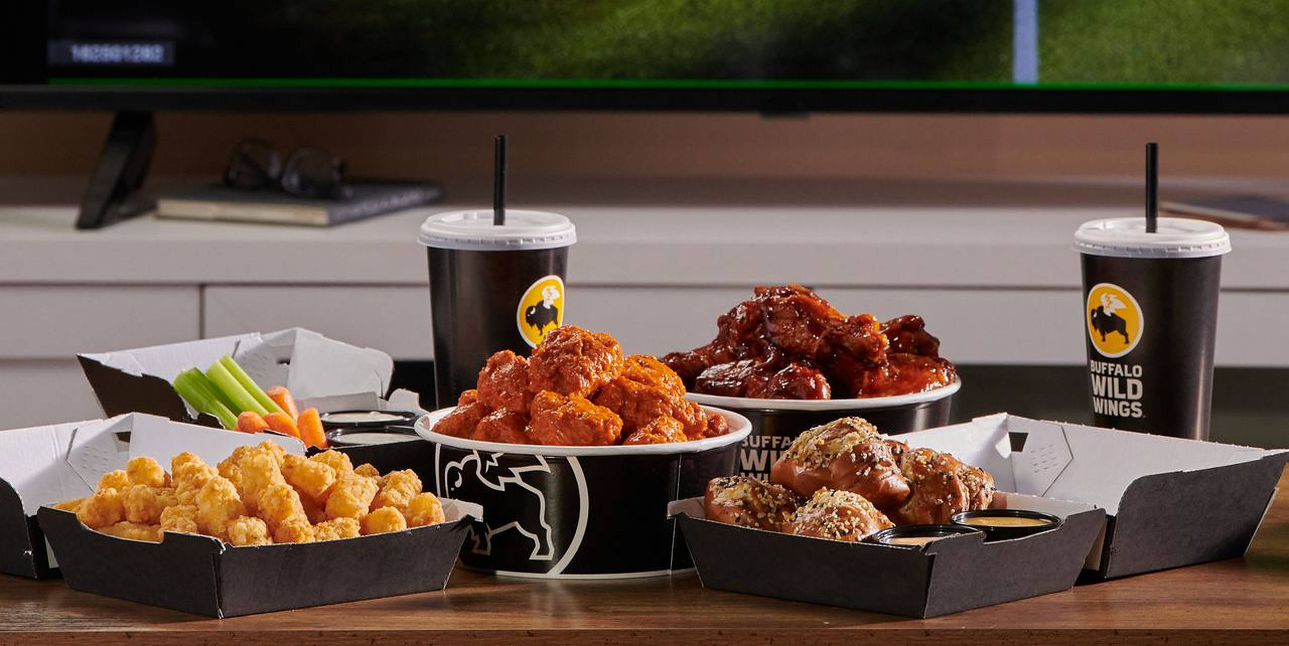 Wild 桌布 壁紙 — Buffalo Wild Wings 美食的誘人拼盤，包括雞翅、薯球和芹菜條，擺放在木桌上。