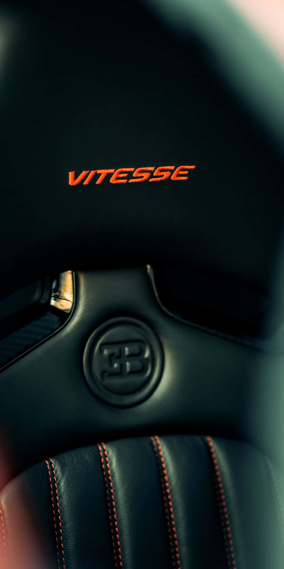 布加迪 桌布 壁紙 — Bugatti Vitesse 方向盤特寫，帶有發光橙色縫線和標誌，襯托深色皮革。