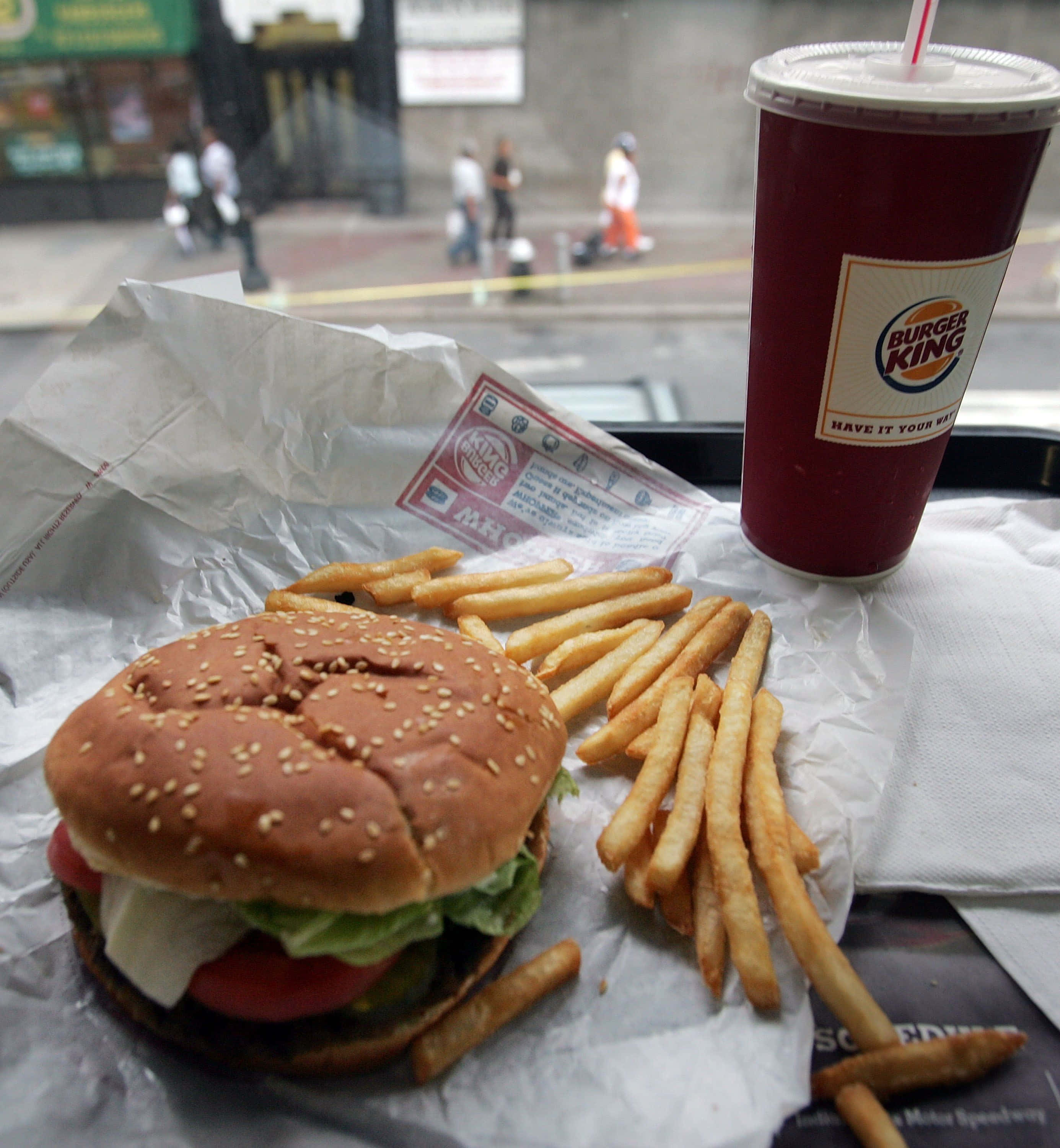 fast food 桌布 壁紙 — Burger King 漢堡和薯條的特寫，放在托盤上，附有飲料杯，從窗戶俯瞰繁忙的街道。