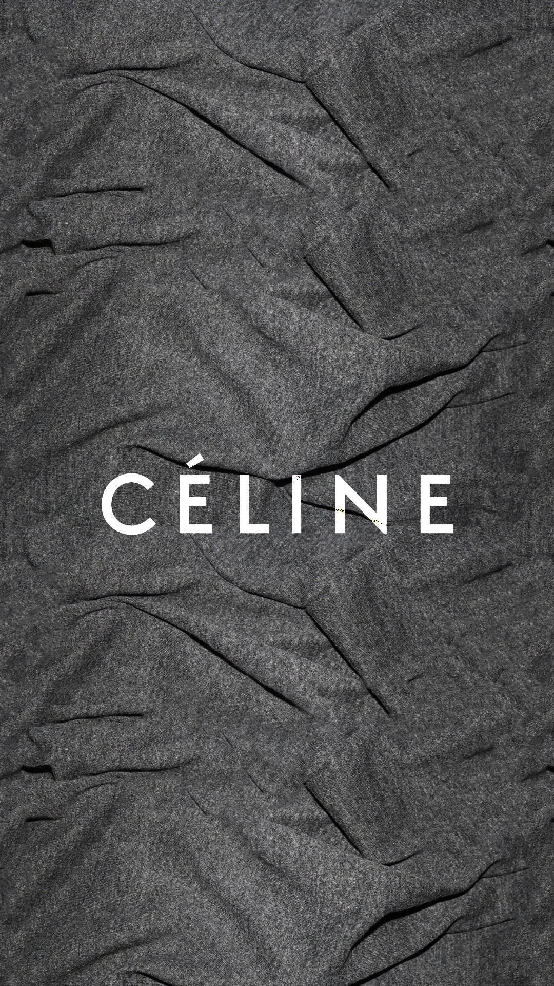 品牌 桌布 壁紙 — CÉLINE 這個詞以清晰的白色字體印在質感粗糙的深灰色皺褶布料表面上。
