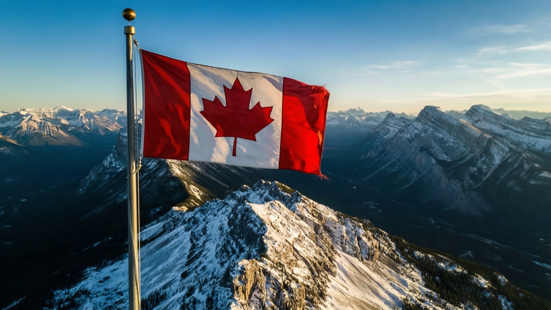 Canada Flag 桌布 壁紙 — 加拿大國旗在白雪覆蓋的山頂上驕傲飄揚，背景是晴朗的藍天和遠處的雪山山脈。