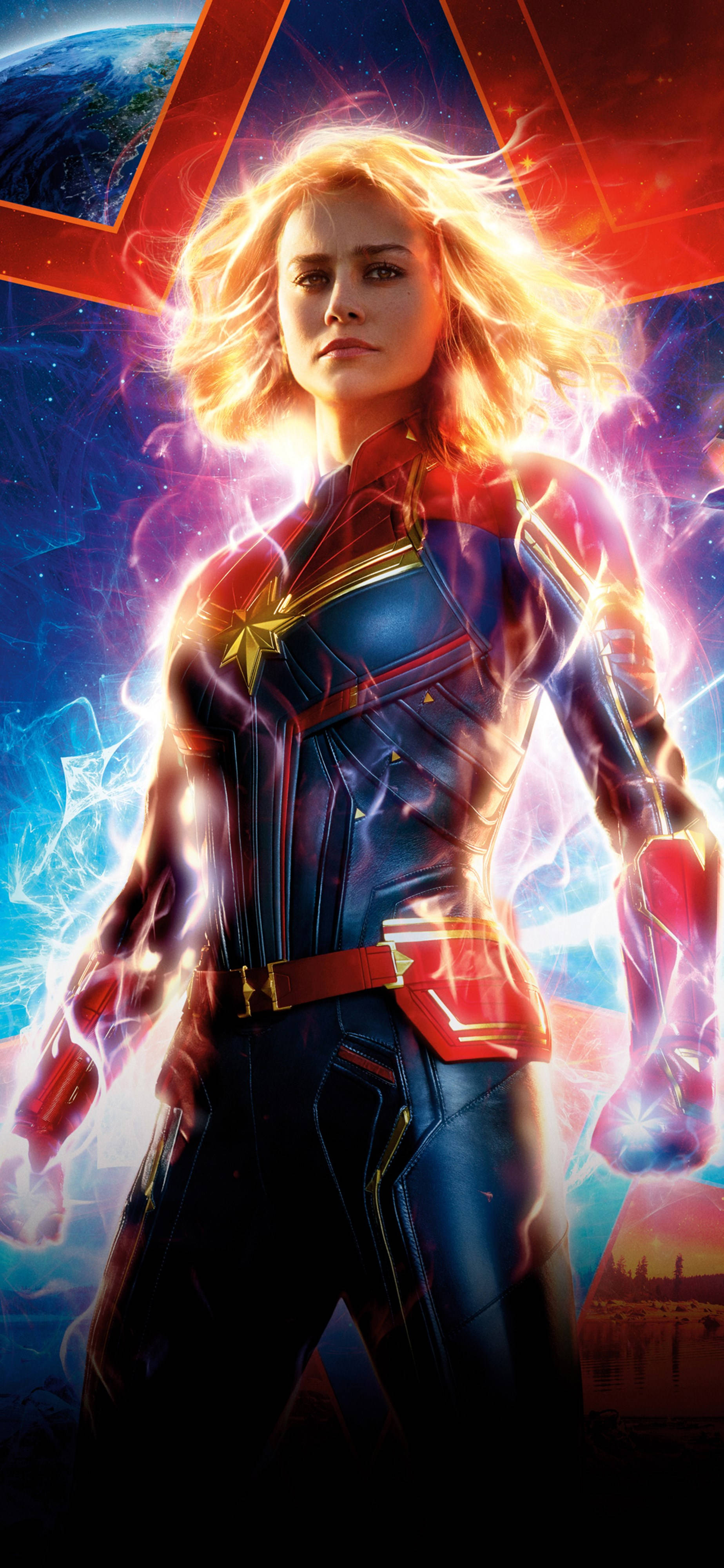 桌布 壁紙 — Captain Marvel 在一個宇宙環境中英勇地站立，帶有發光的能量效果和背景中的一顆行星。