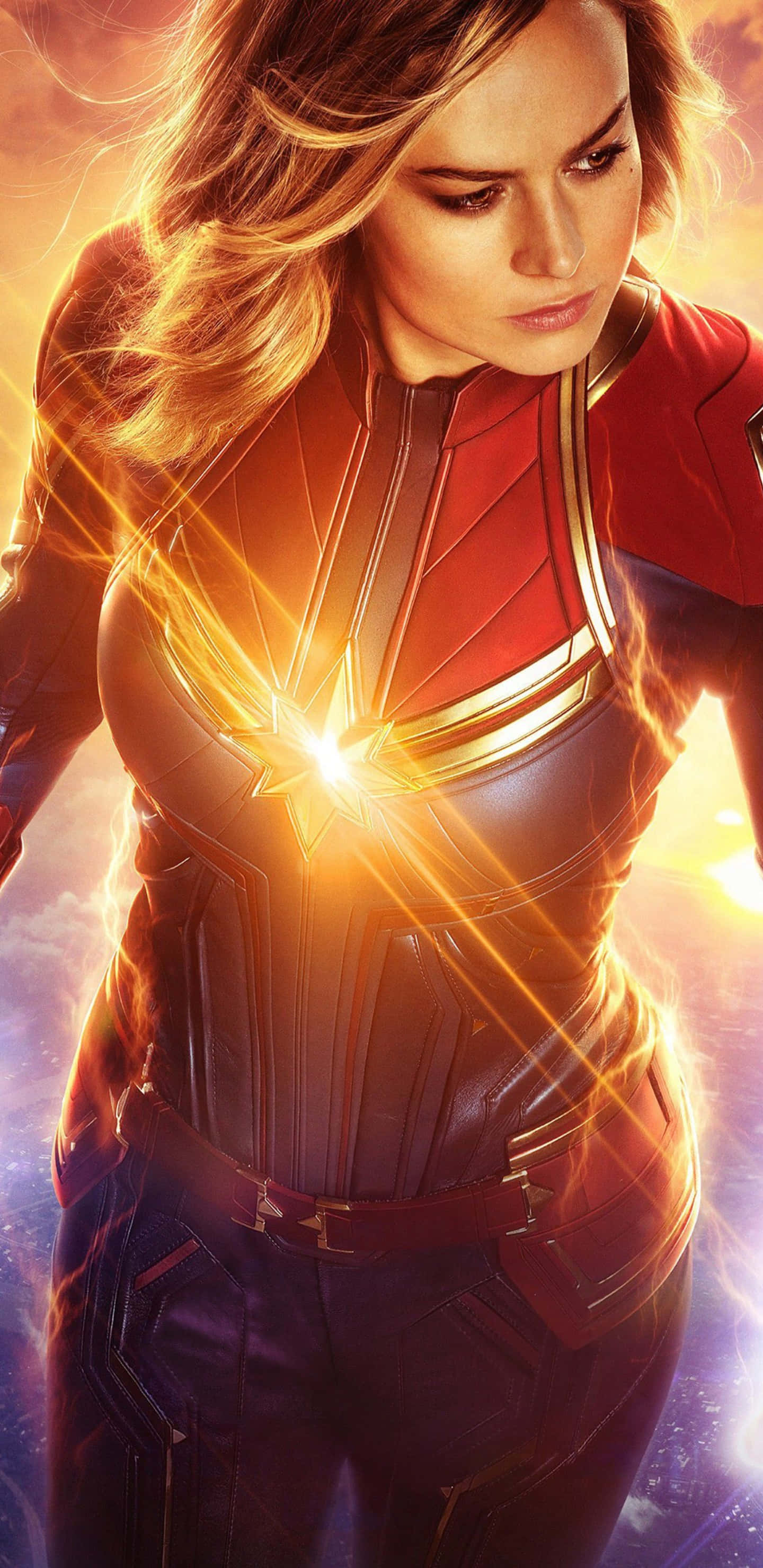 Pixel 3xl Captain Marvel 桌布 壁紙 — Captain Marvel 身穿紅藍戰衣，金色能量從胸口迸發，在宇宙背景下散發力量。
