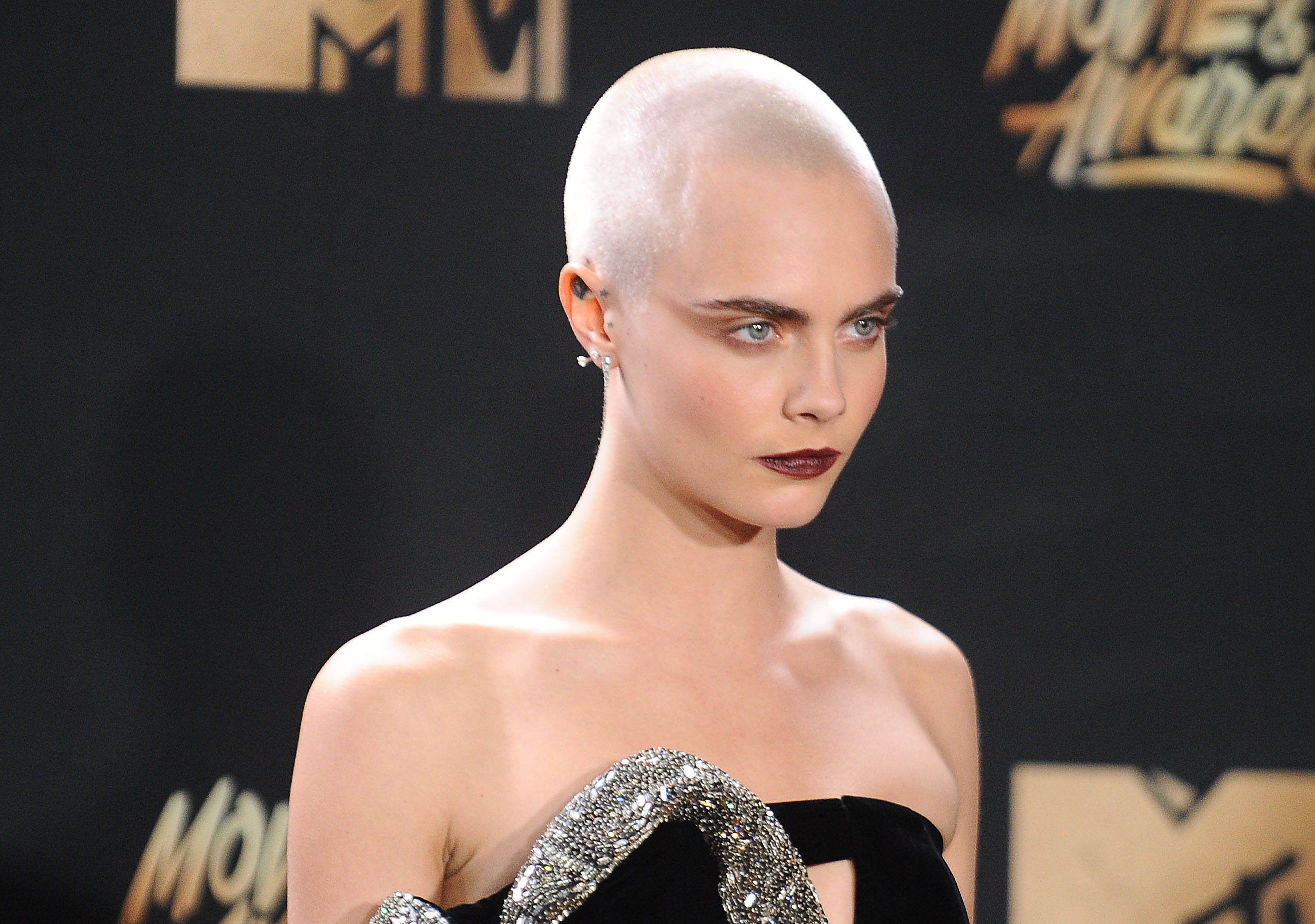 Cara 桌布 壁紙 — Cara Delevingne 剃光頭，搭配大膽紅唇，在 MTV 電影電視獎紅毯上擺姿勢。