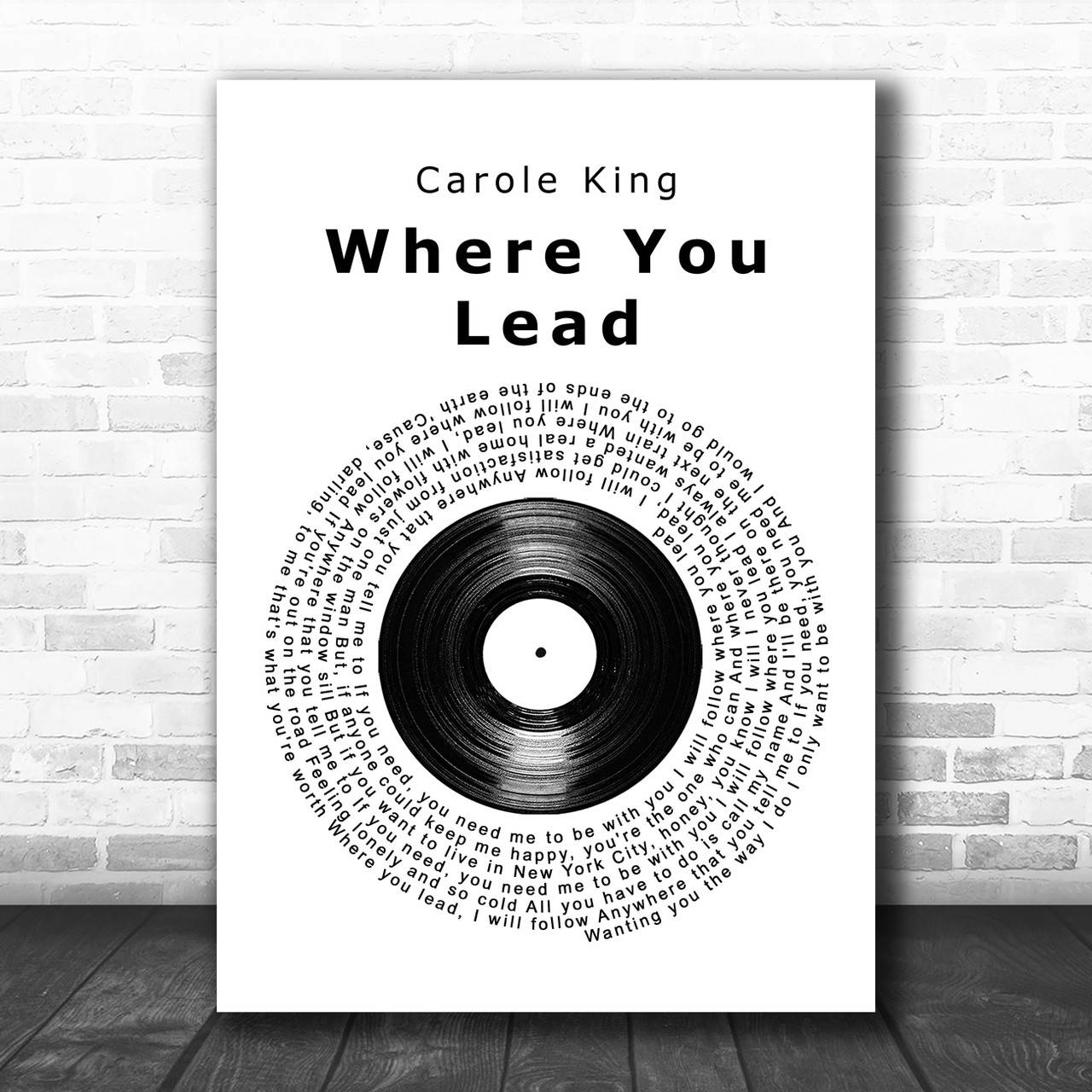 band 桌布 壁紙 — Carole King 的《Where You Lead》極簡黑白海報，歌詞圍繞黑膠唱片形成圓圈，安裝在白色磚牆上，下方是深色木地板。