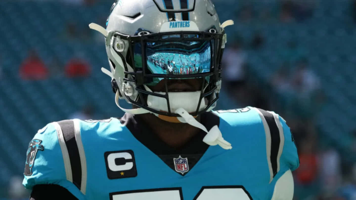  壁紙 — 一位卡羅萊納黑豹隊NFL美式足球員，身穿淺藍色球衣，頭盔帶有反光面罩，站在體育場內。