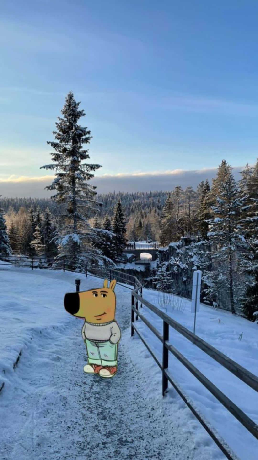  壁紙 — 一隻卡通狗站在雪地上，旁邊有圍欄，圍欄旁有積雪的松樹和遠處的橋樑，天空清澈湛藍。