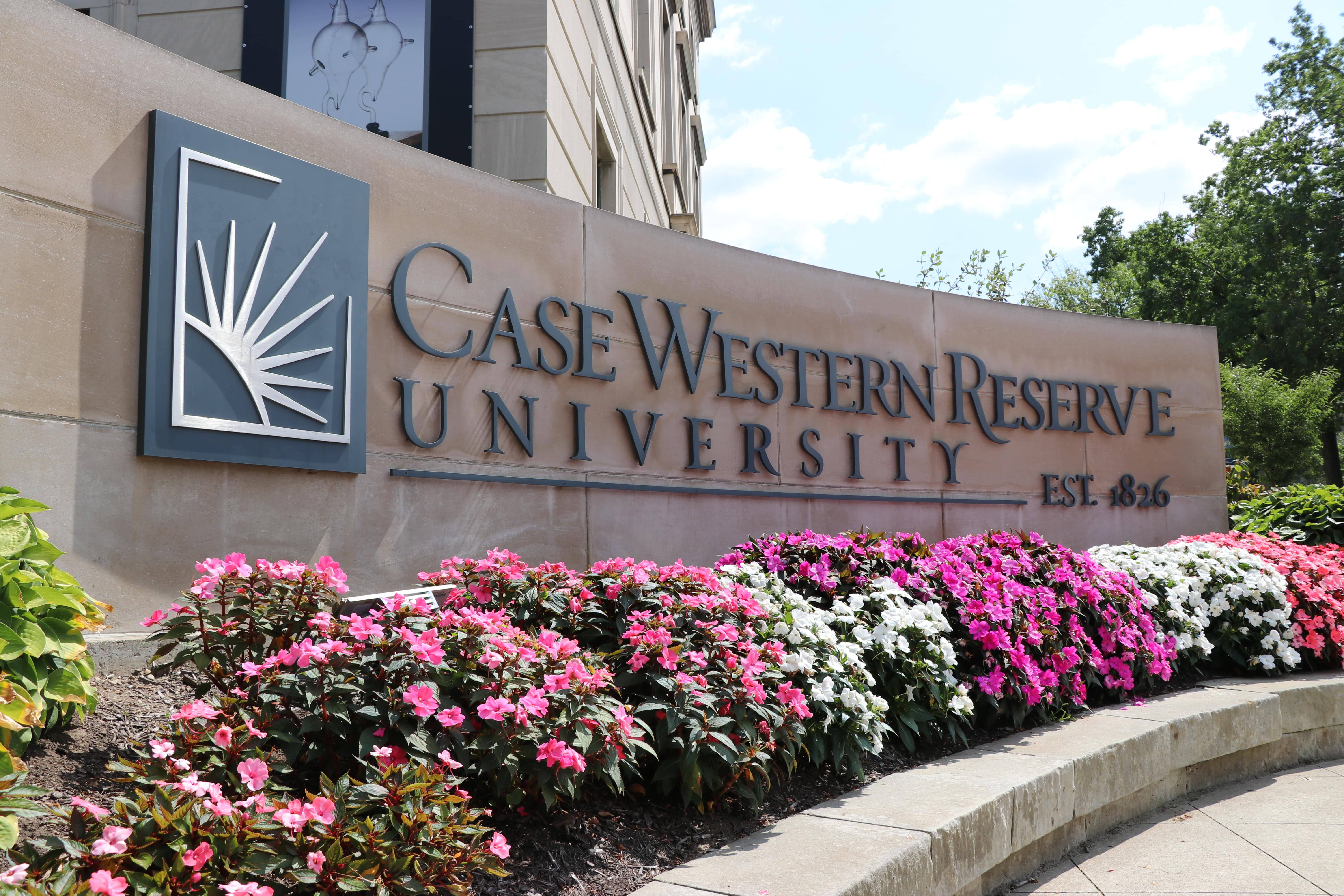 學校 桌布 壁紙 — Case Western Reserve University 標誌，前方有粉紅色和白色花朵，背景是明亮的藍天。