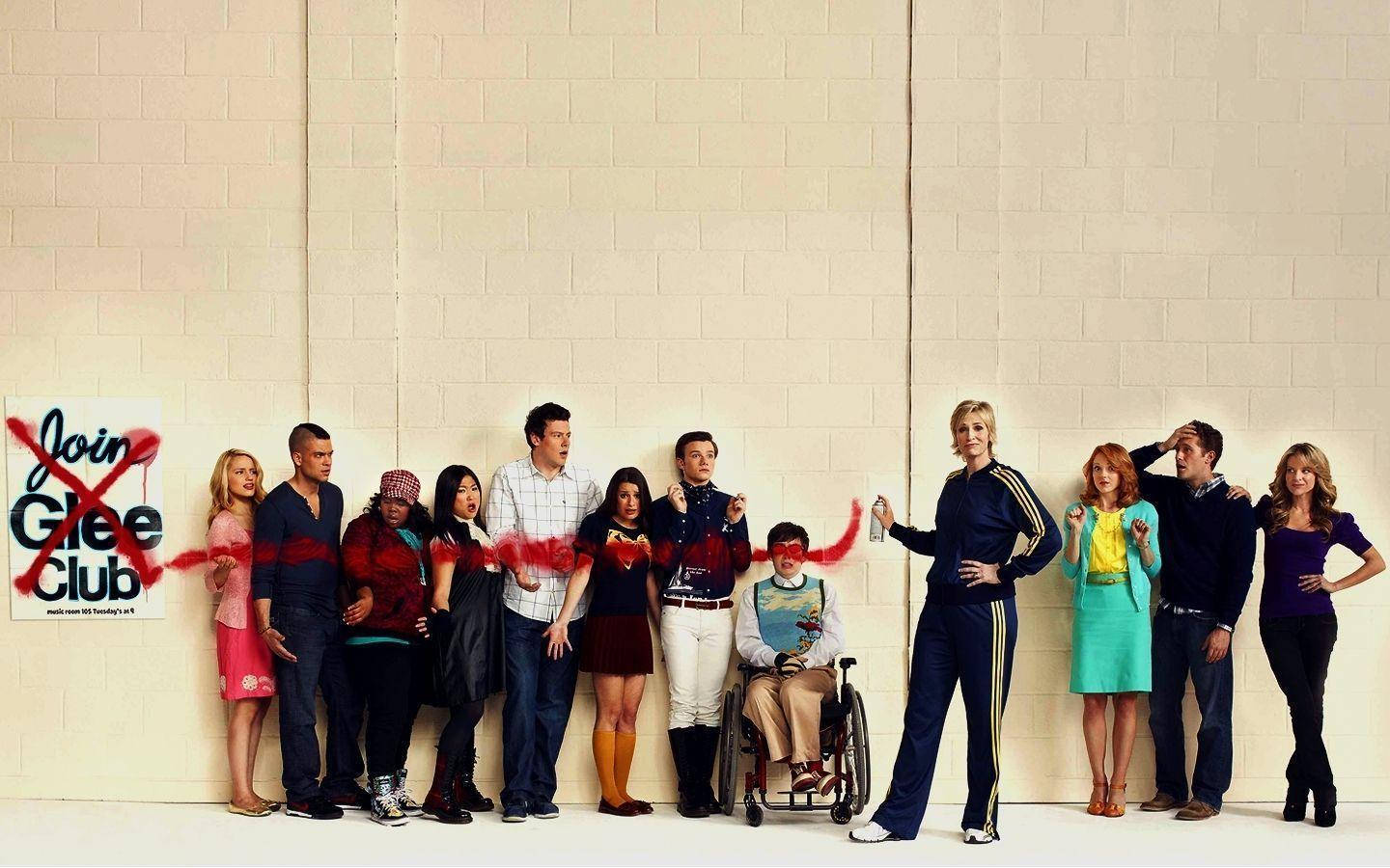 tv 桌布 壁紙 — Cast of Glee 自信地在米色磚牆旁邊擺姿勢，牆上有個用紅色噴漆劃掉的 'Join Glee Club' 標誌。