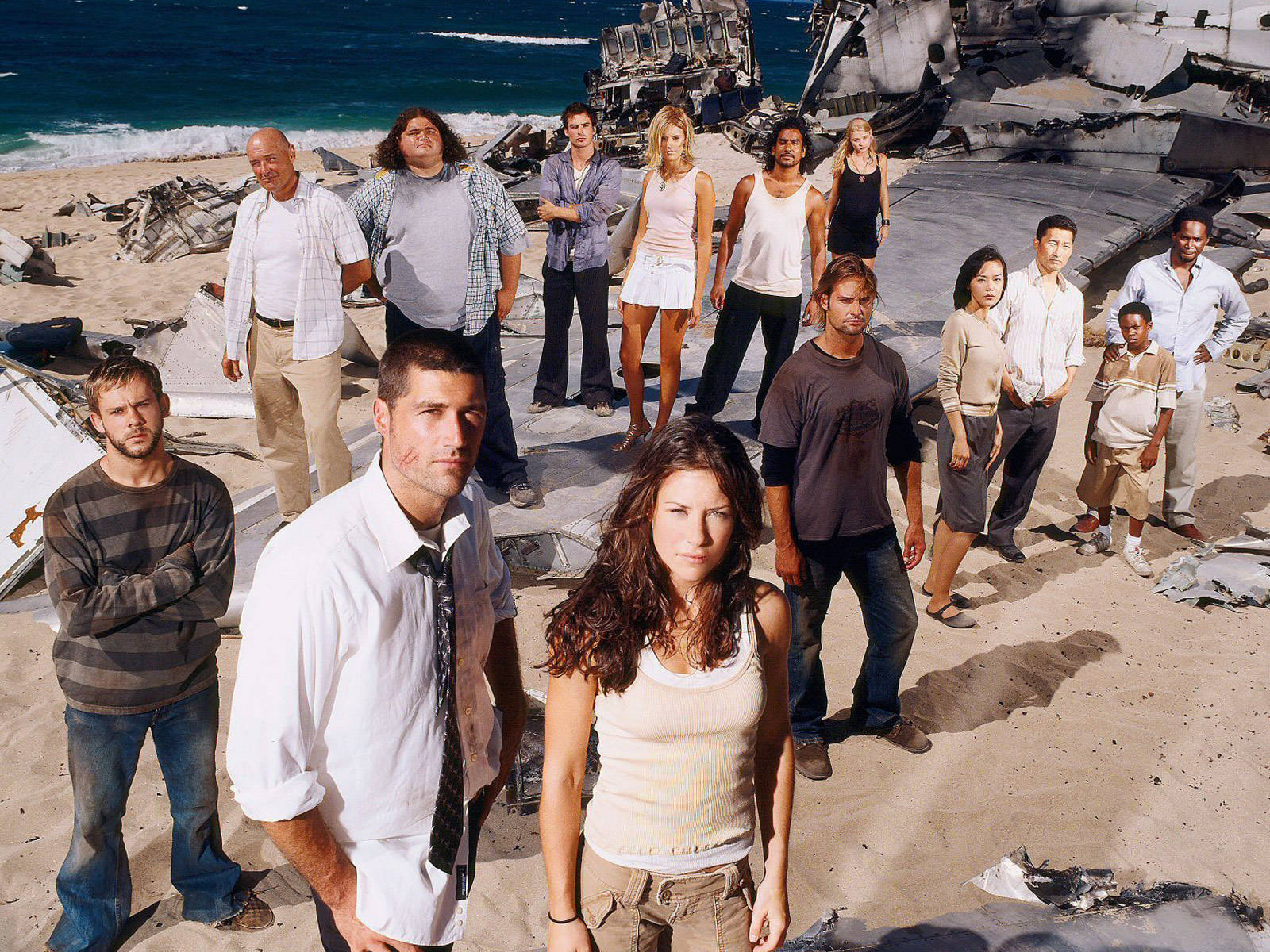 海灘 桌布 壁紙 — Cast of Lost 站在陽光明媚的海灘上，周圍是墜毀飛機的殘骸，海浪在附近拍打。