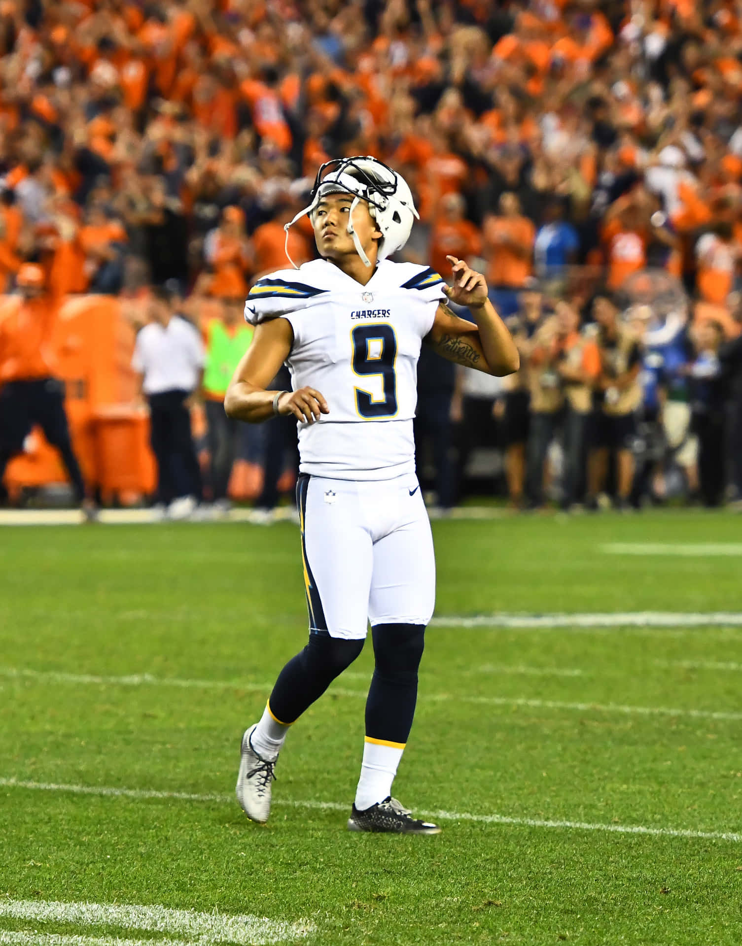  壁紙 — 一位身穿白色球衣、號碼9的Chargers美式足球員在綠色球場上、球場燈光下慶祝，背景有身穿橙色衣服的球迷。