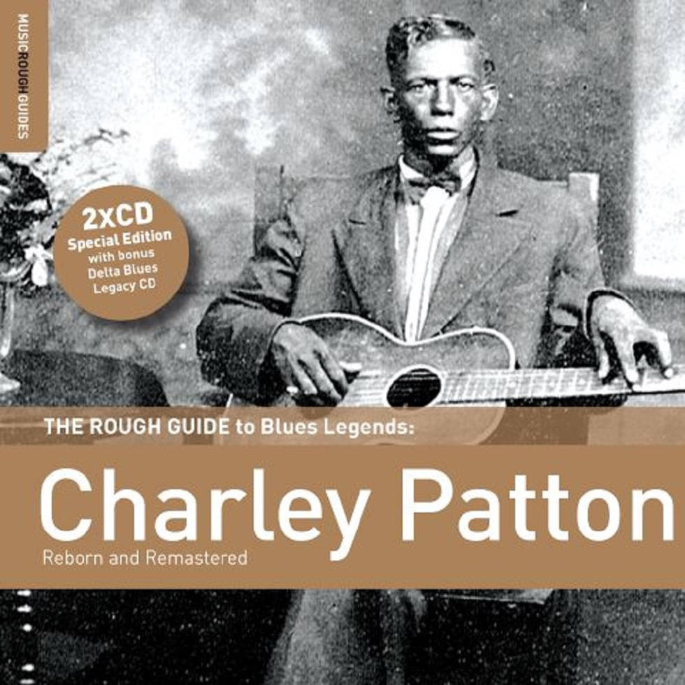 吉他動圖 桌布 壁紙 — Charley Patton 坐著拿著木吉他的復古黑白肖像，帶有文字疊加，用於藍調音樂合輯。