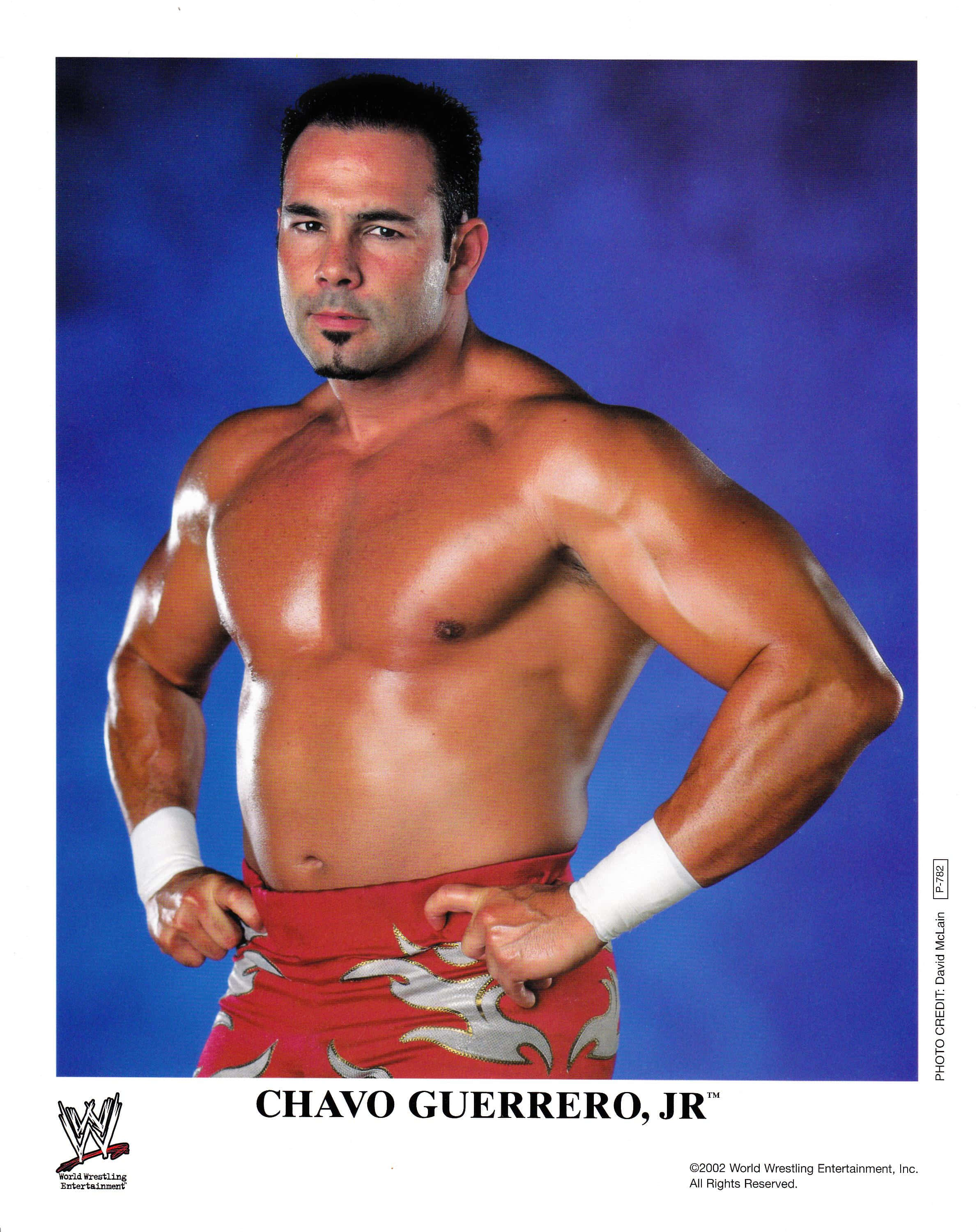 WWE Logo 桌布 壁紙 — Chavo Guerrero Jr. 在充滿活力的藍色攝影棚背景前，赤裸上身，雙手叉腰擺姿勢。