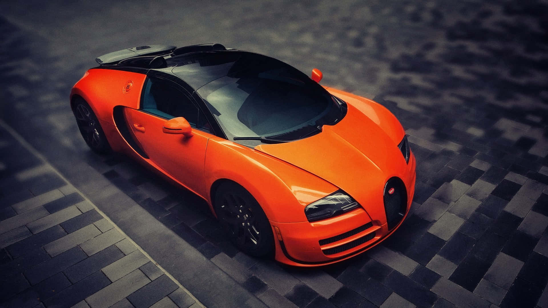 Bugatti Veyron 桌布 壁紙 — 一輛充滿活力的橙色Bugatti Veyron跑車，在戲劇性燈光下停泊在深色棋盤格路面上。