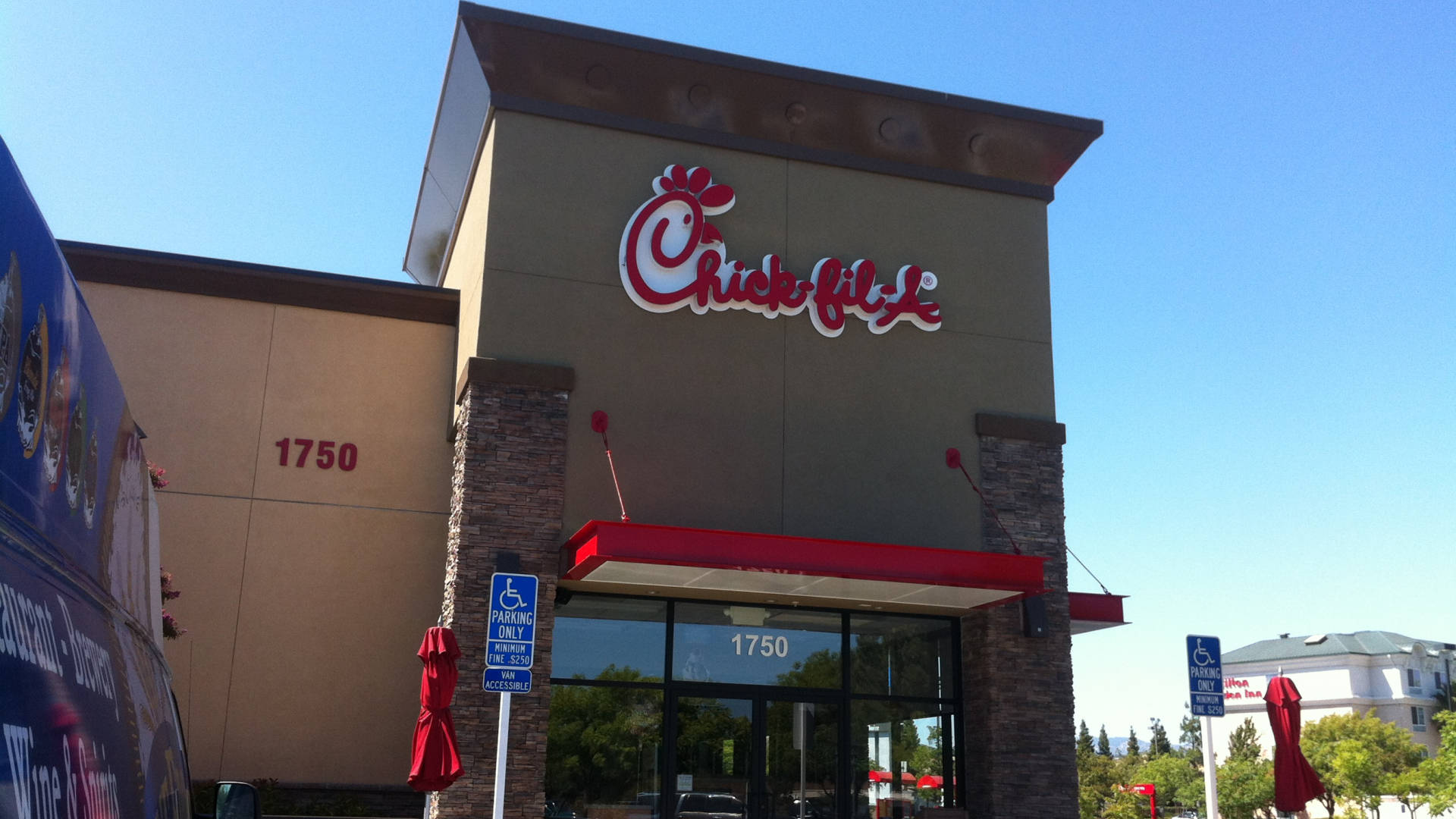 chick 桌布 壁紙 — Chick-fil-A 餐廳建築，在晴朗的藍天下，前方有紅色遮陽篷和關閉的雨傘。
