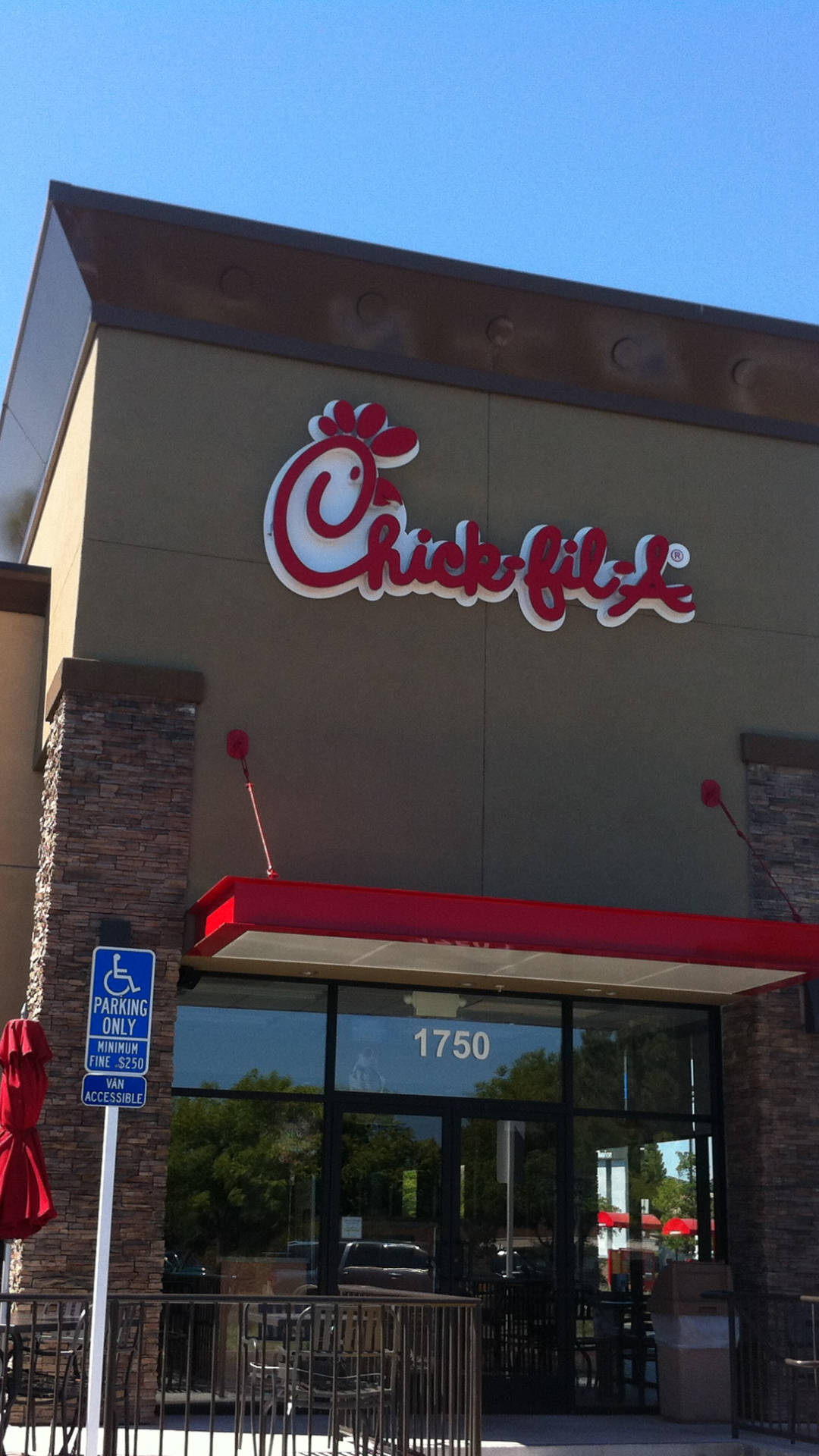 chick 桌布 壁紙 — Chick-fil-A 餐廳建築在晴朗藍天下，紅色遮陽篷和殘疾人士停車標誌清晰可見。