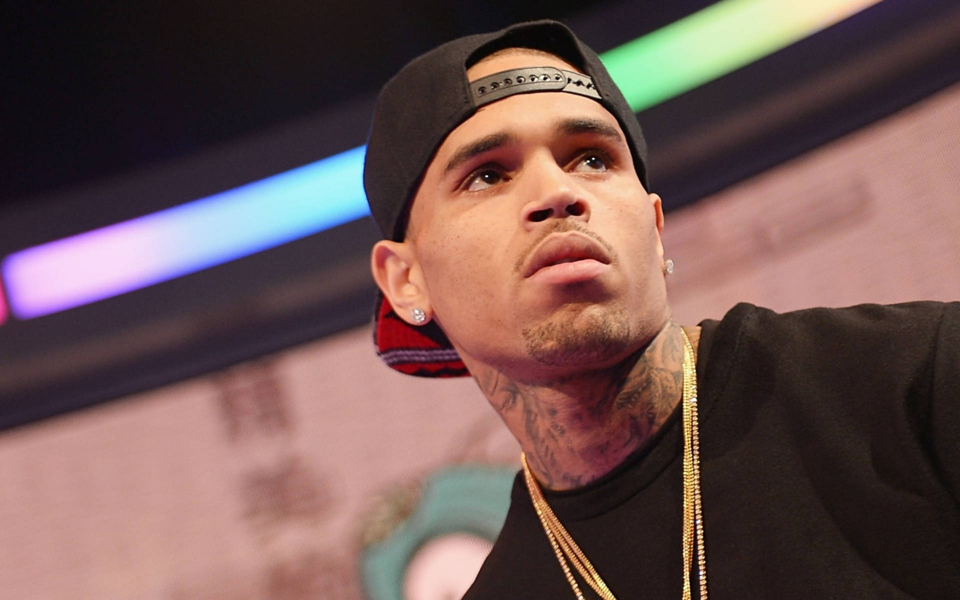 Chris Brown 桌布 壁紙 — Chris Brown 戴著黑色帽子和金鏈向上看，脖子上的刺青清晰可見的特寫。