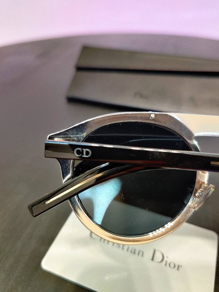 Christian Dior 太陽眼鏡，金屬鏡框搭配黑色鏡片，放置在品牌盒上。 — Dior 動態 壁紙
