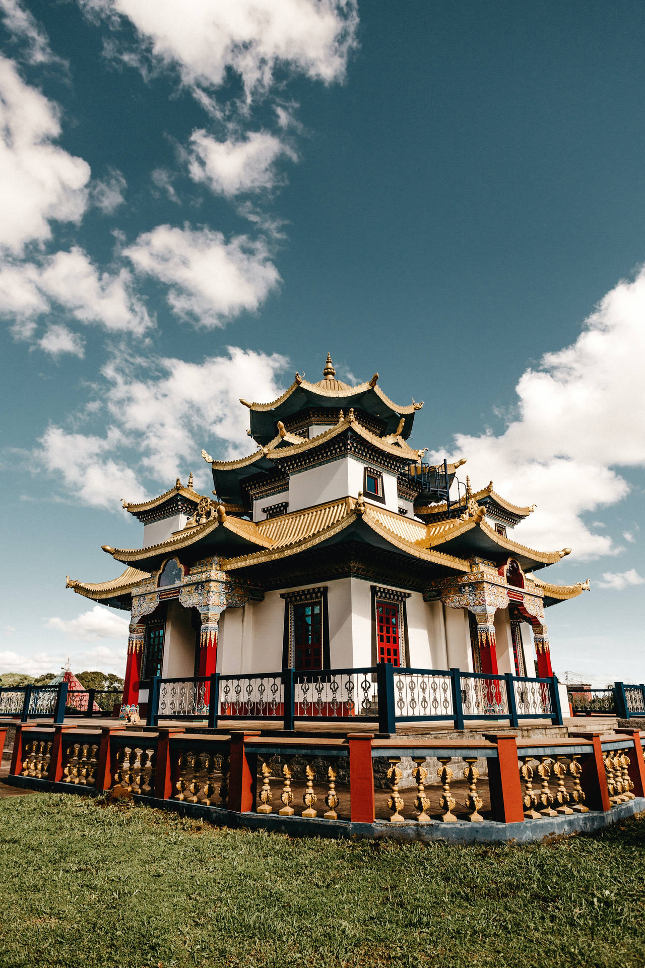 一座傳統亞洲寺廟，擁有金色屋頂和紅色柱子，在藍天白雲下。 — 中式房屋壁紙 壁紙