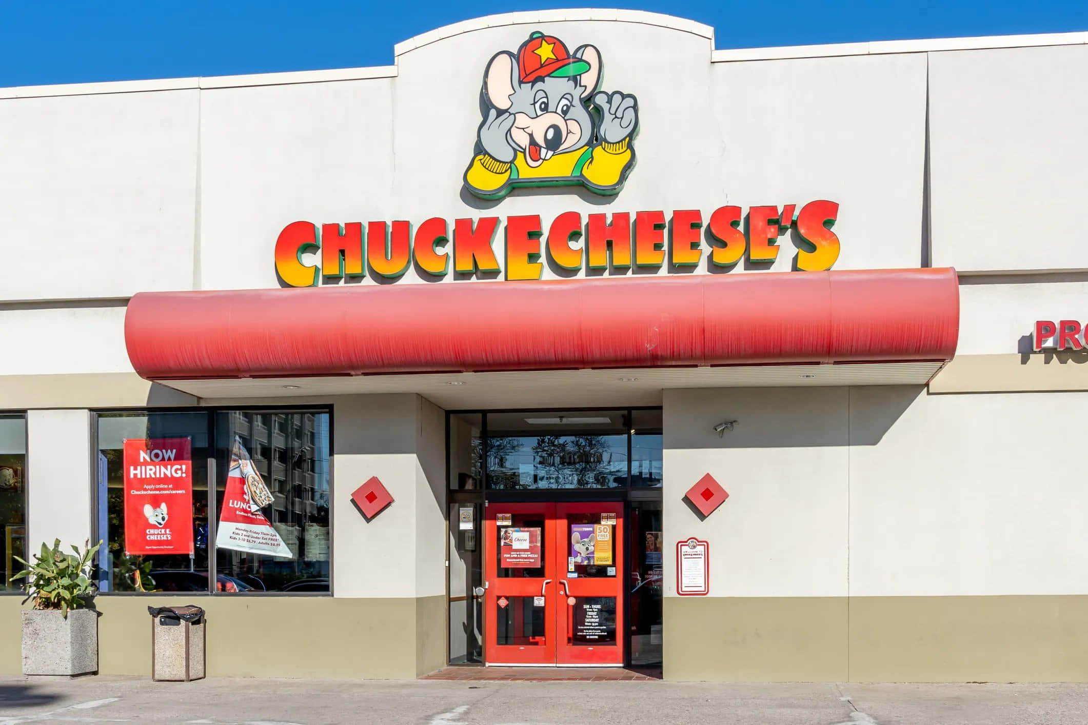 查克芝士 桌布 壁紙 — Chuck E Cheese 的鮮紅色入口，在晴朗藍天下，門上有卡通吉祥物。
