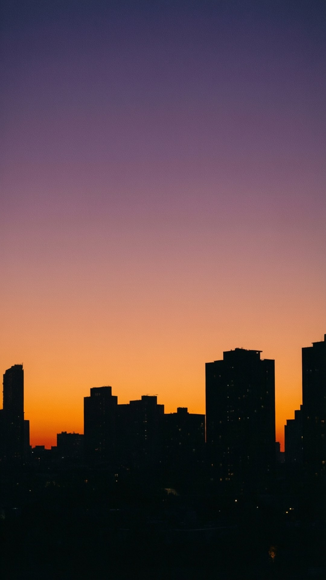 Dusk Cityscape 壁紙 — 城市天際線在充滿活力的紫色和橙色日落天空下呈現剪影。