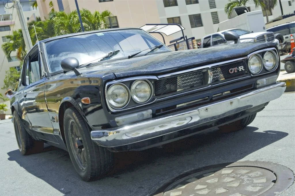 經典黑色日產GTR轎車停放在陽光明媚的市區街道上，旁邊有棕櫚樹。 — 保羅·沃克汽車 壁紙