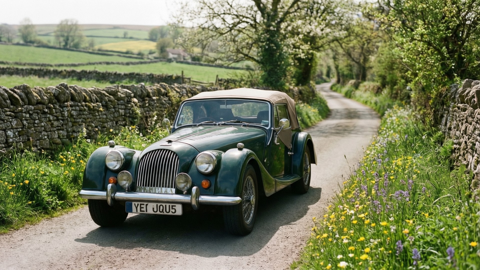 Morgan Plus Six 桌布 壁紙 — 一輛經典綠色摩根敞篷跑車在明媚日光下行駛於蜿蜒的鄉間小路，小路兩旁是石牆和野花。